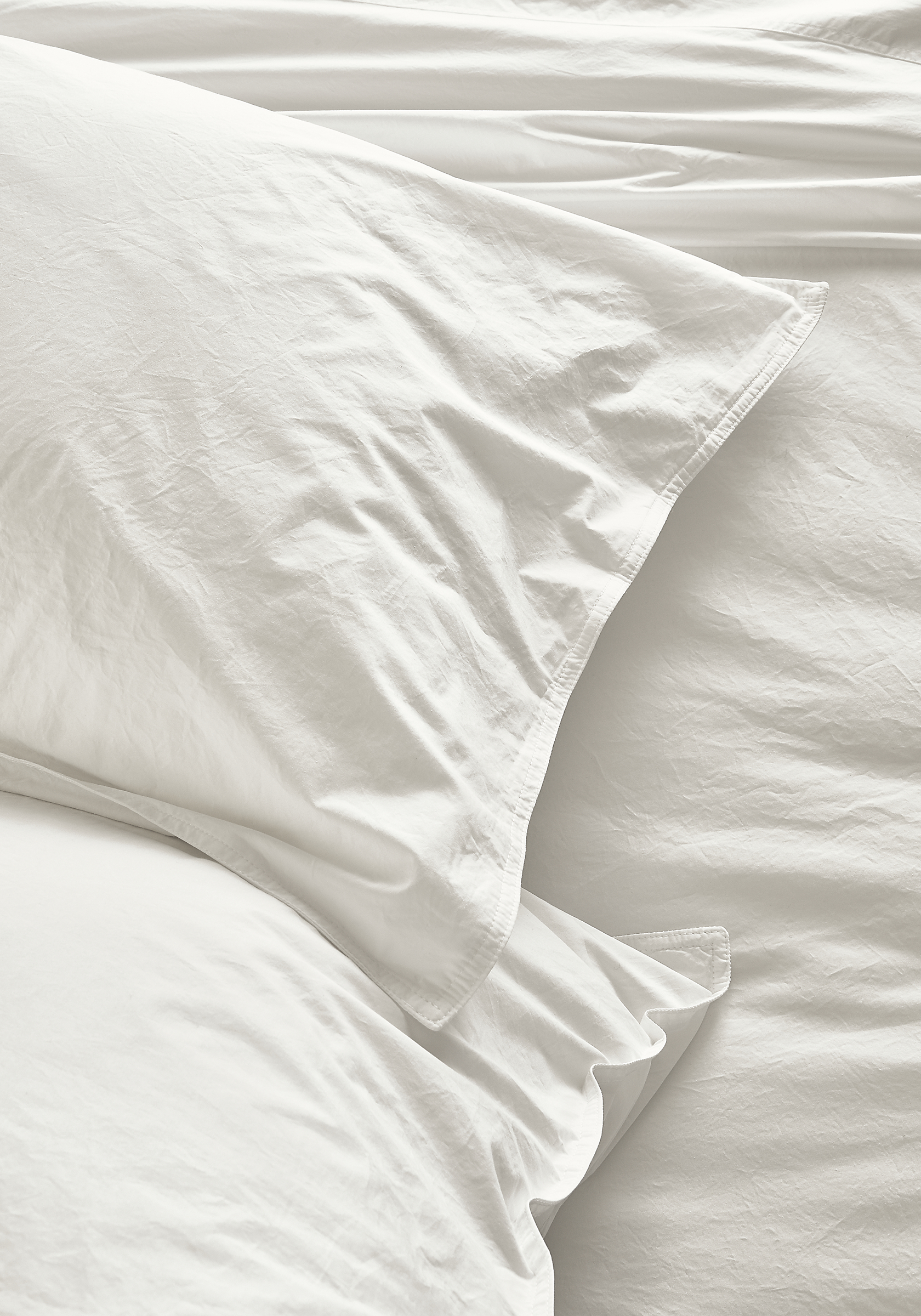 Detail view of Signature Percale standard sham and fitted sheet in white.