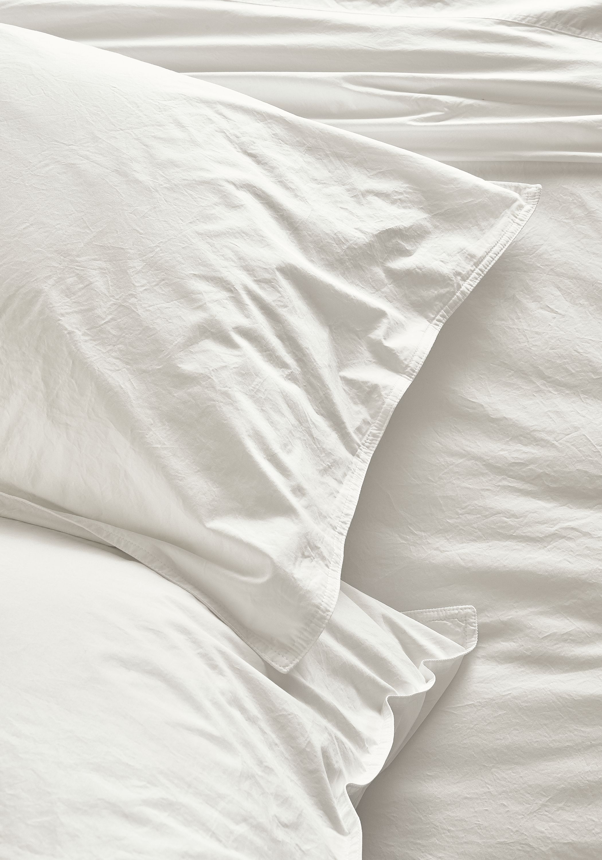 Detail view of Signature Percale standard sham and fitted sheet in white.