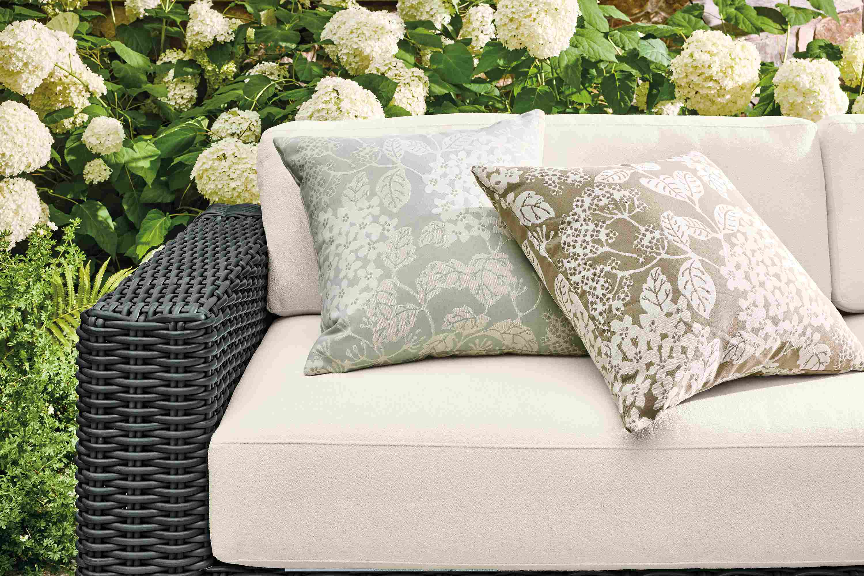 Petals outdoor pillow in sky and pebble on a Madura sofa in dusk ivory and charcoal weave.