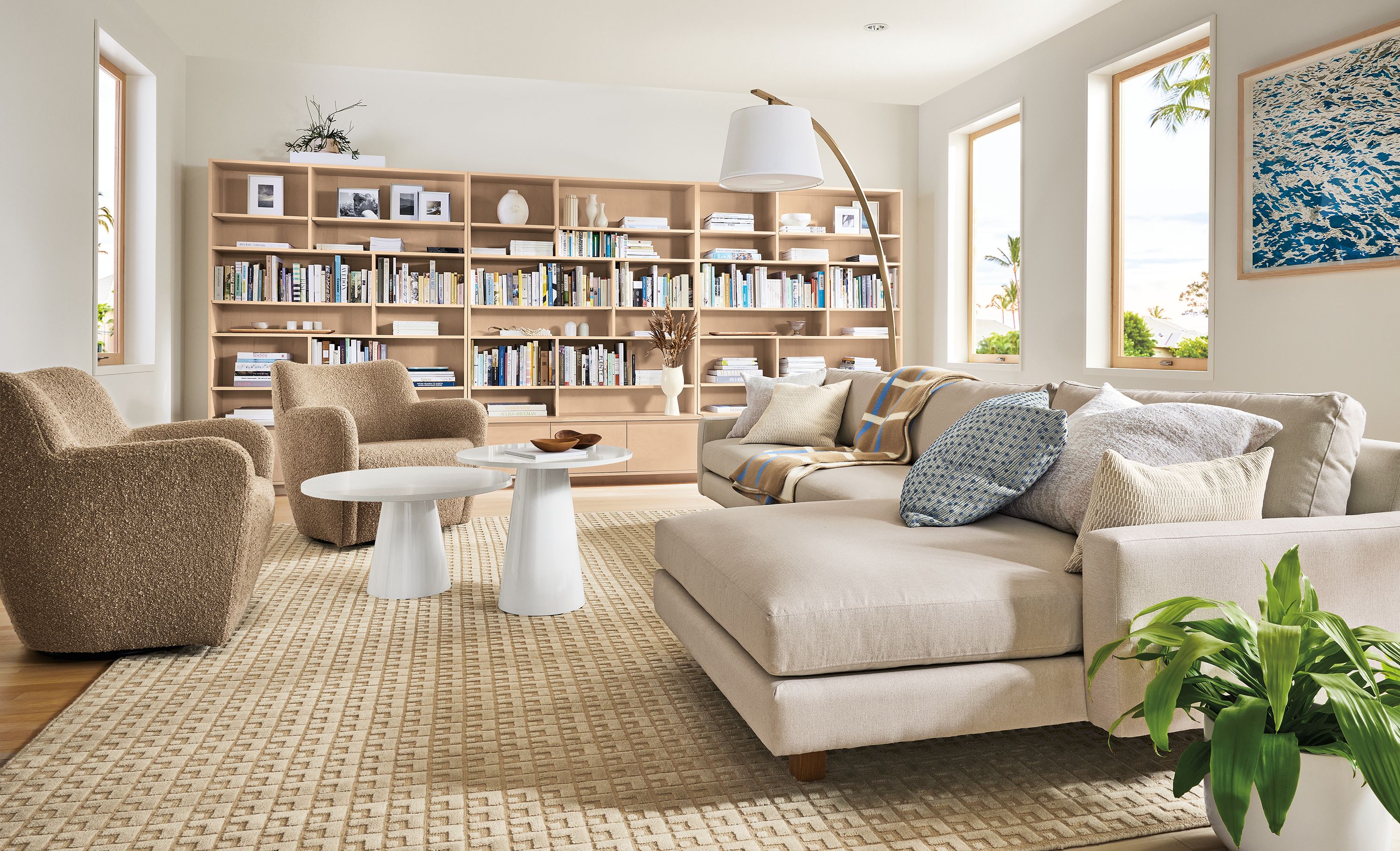 Living room with pierson sofa with chaise in Hines oatmeal, two lily chairs in dornick camel and keaton bookcases in sand on maple.