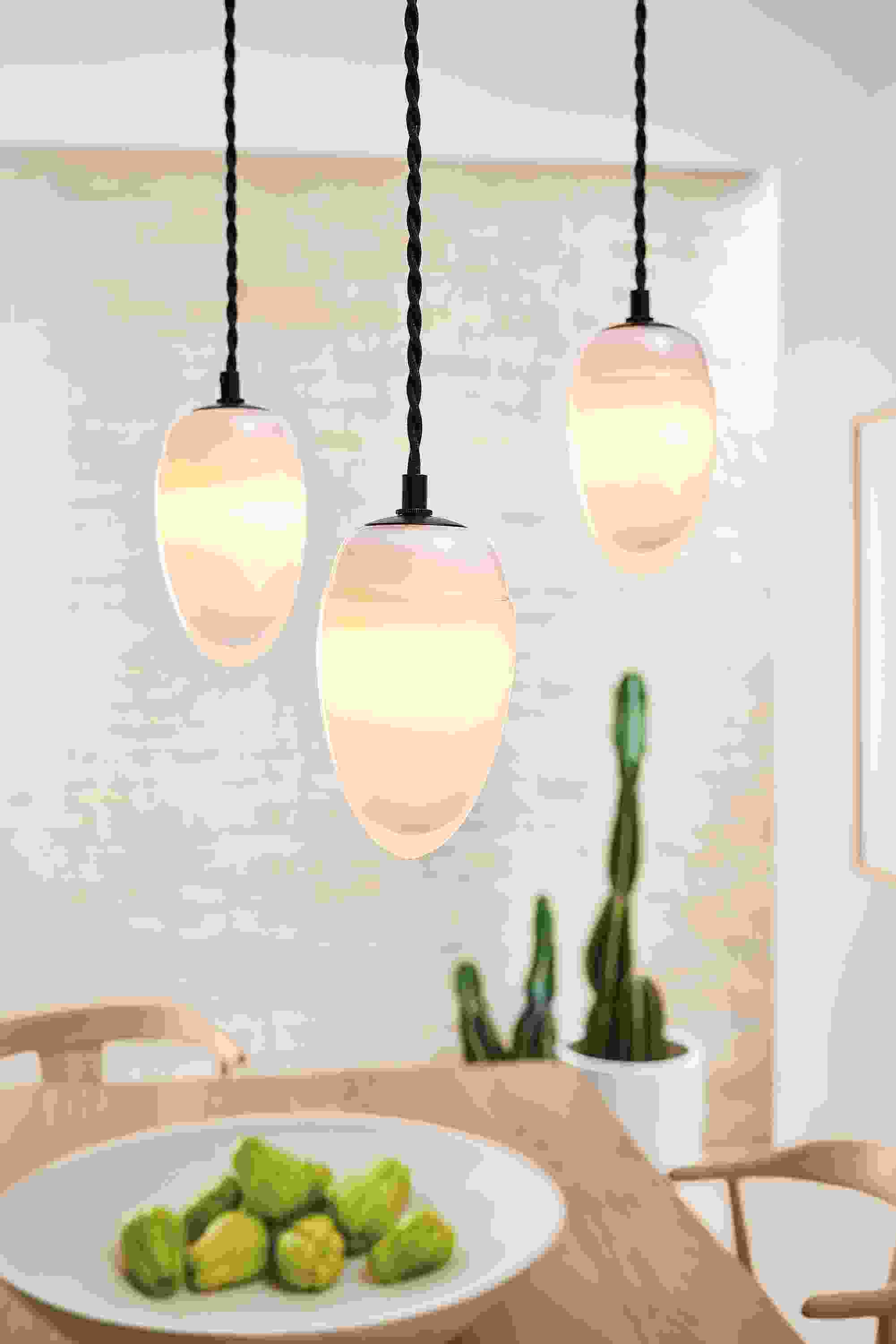 Detail of polar pendants set of 3 in milky white glass above a Colby dining table.