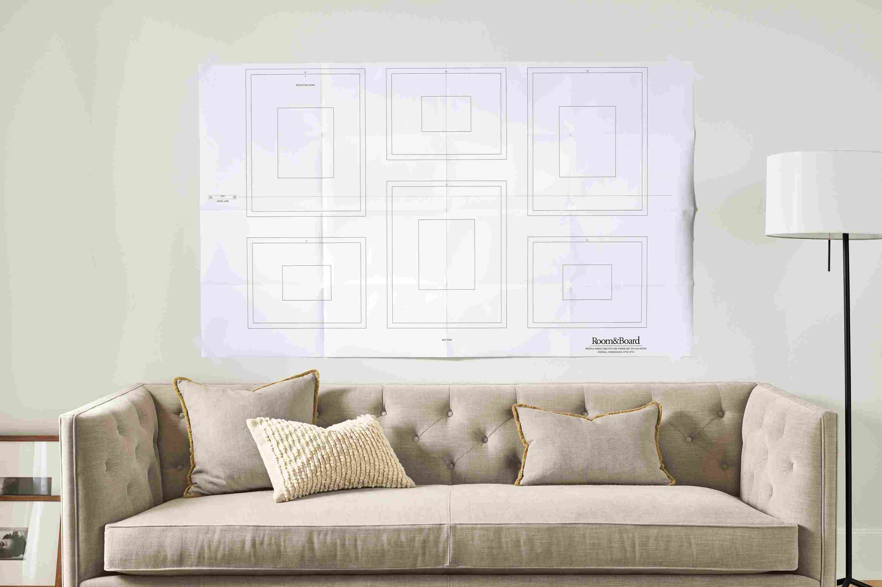 detail of paper template for picture frames taped to wall above sofa