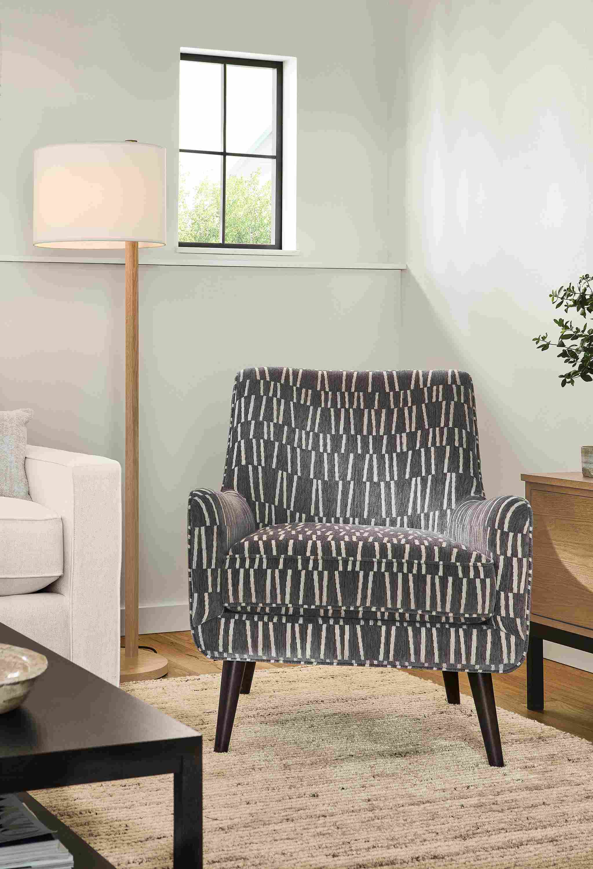 Living room with Quinn chair in Hampden Charcoal, Everett 61-high floor lamp in rye on red oak and Norfolk rug in taupe.