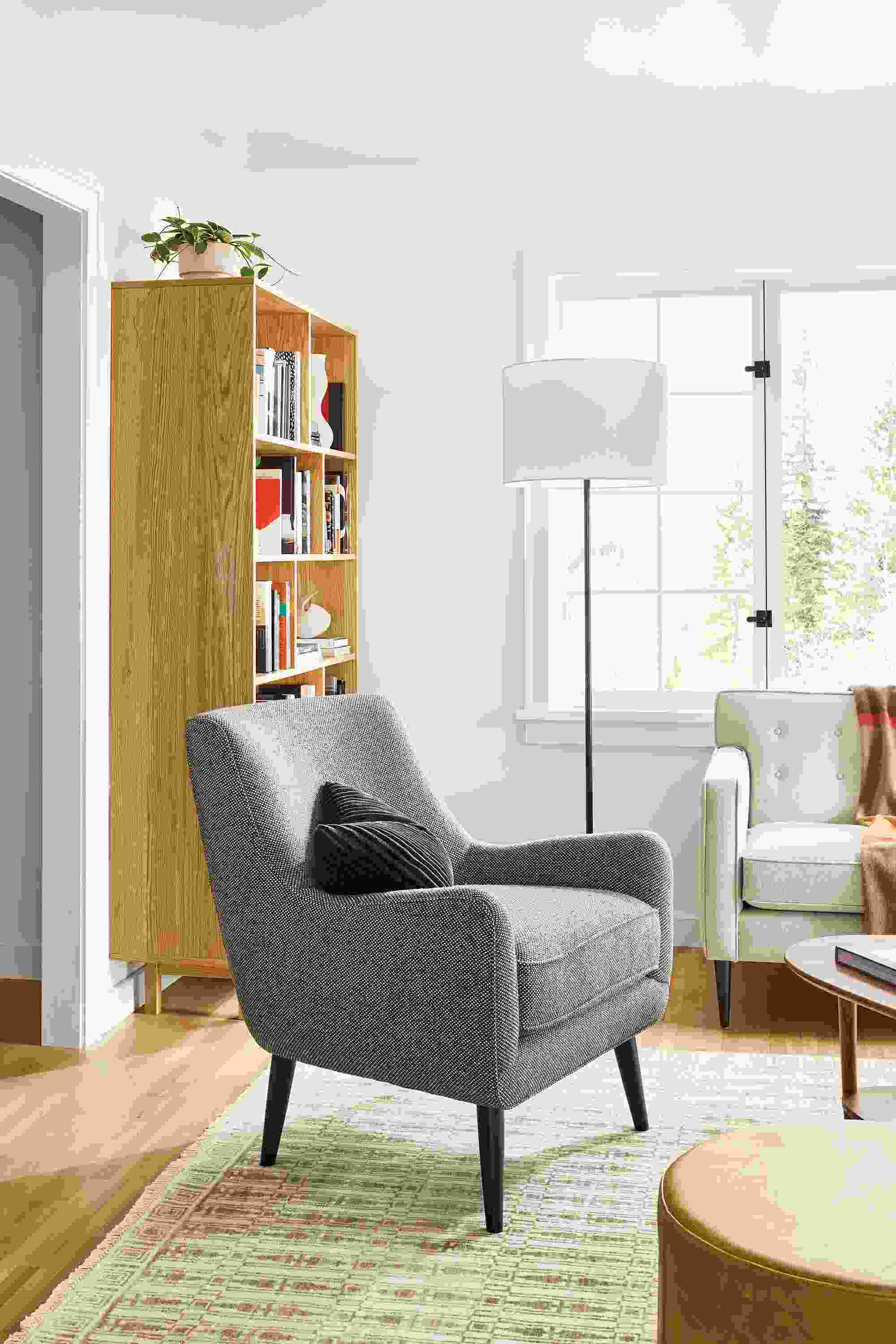 Living room with Quinn chair in Arin Graphite, Tulum rug in taupe and Aero ottoman in Vento Camel.