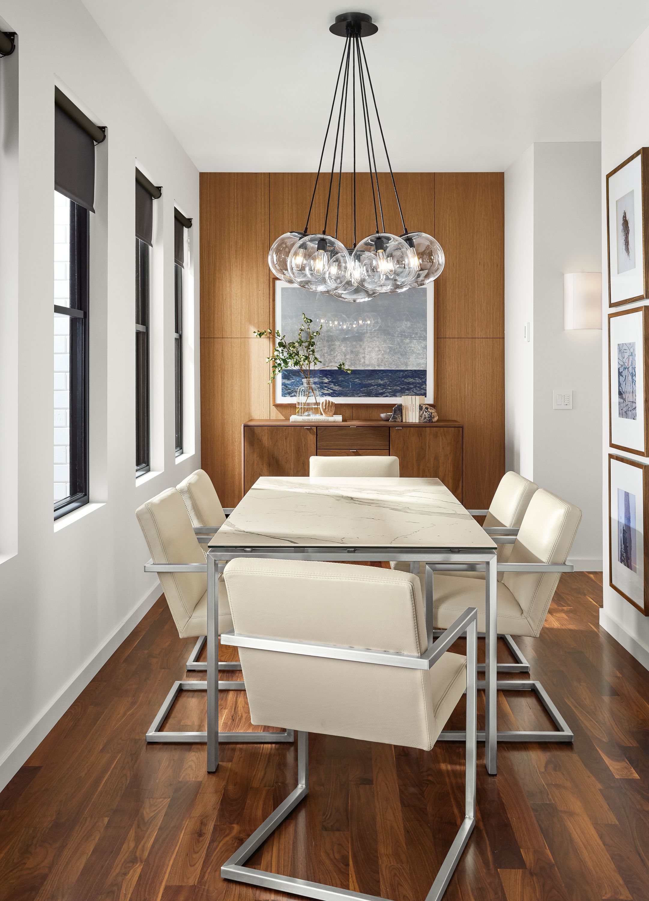 Detail of Rand dining table with stainless steel base and white marbled ceramic top and 6 Lira arm chairs.