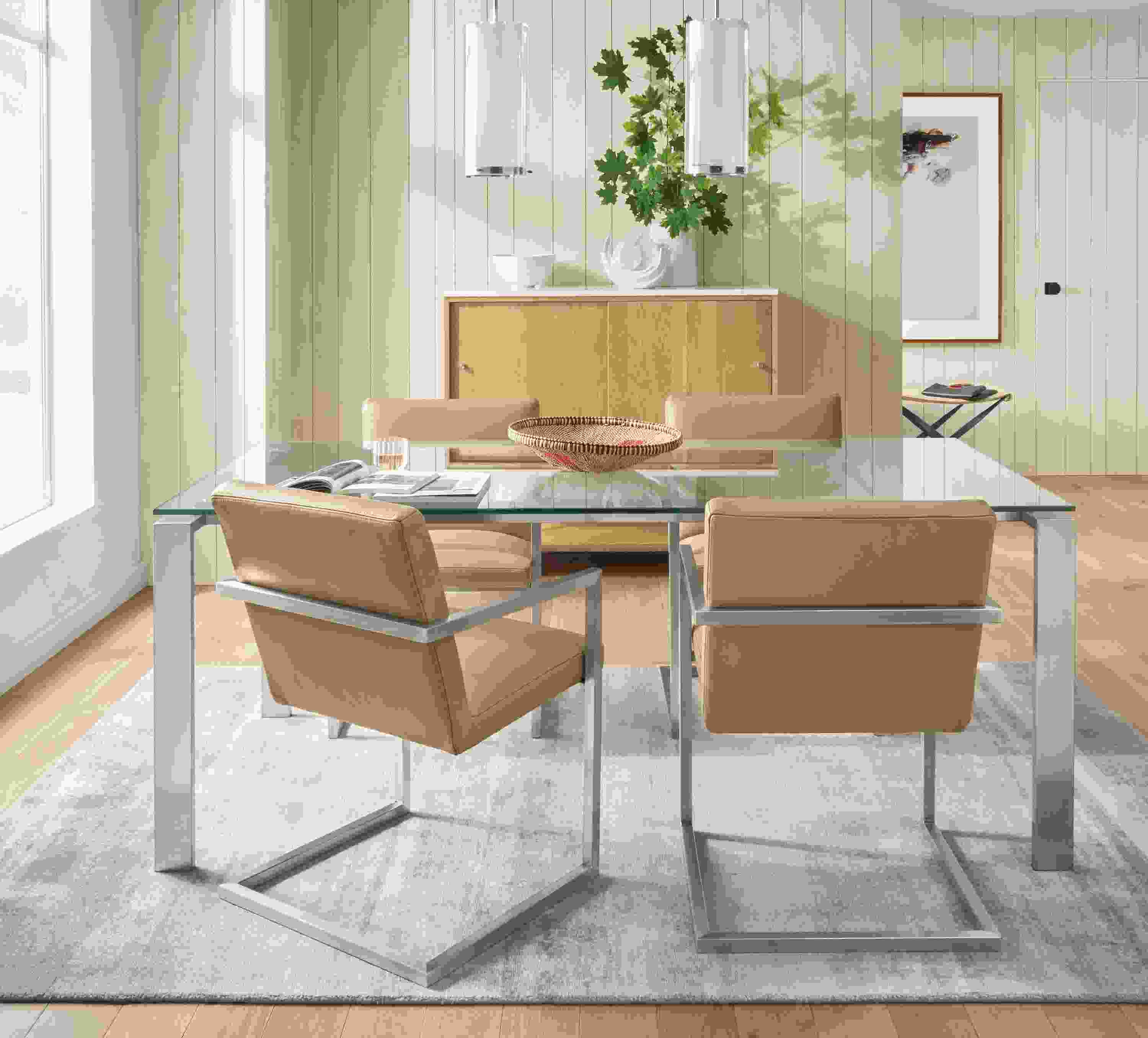 Detail of Rand table with glass top and stainless steel base with Lira leather arm chairs.
