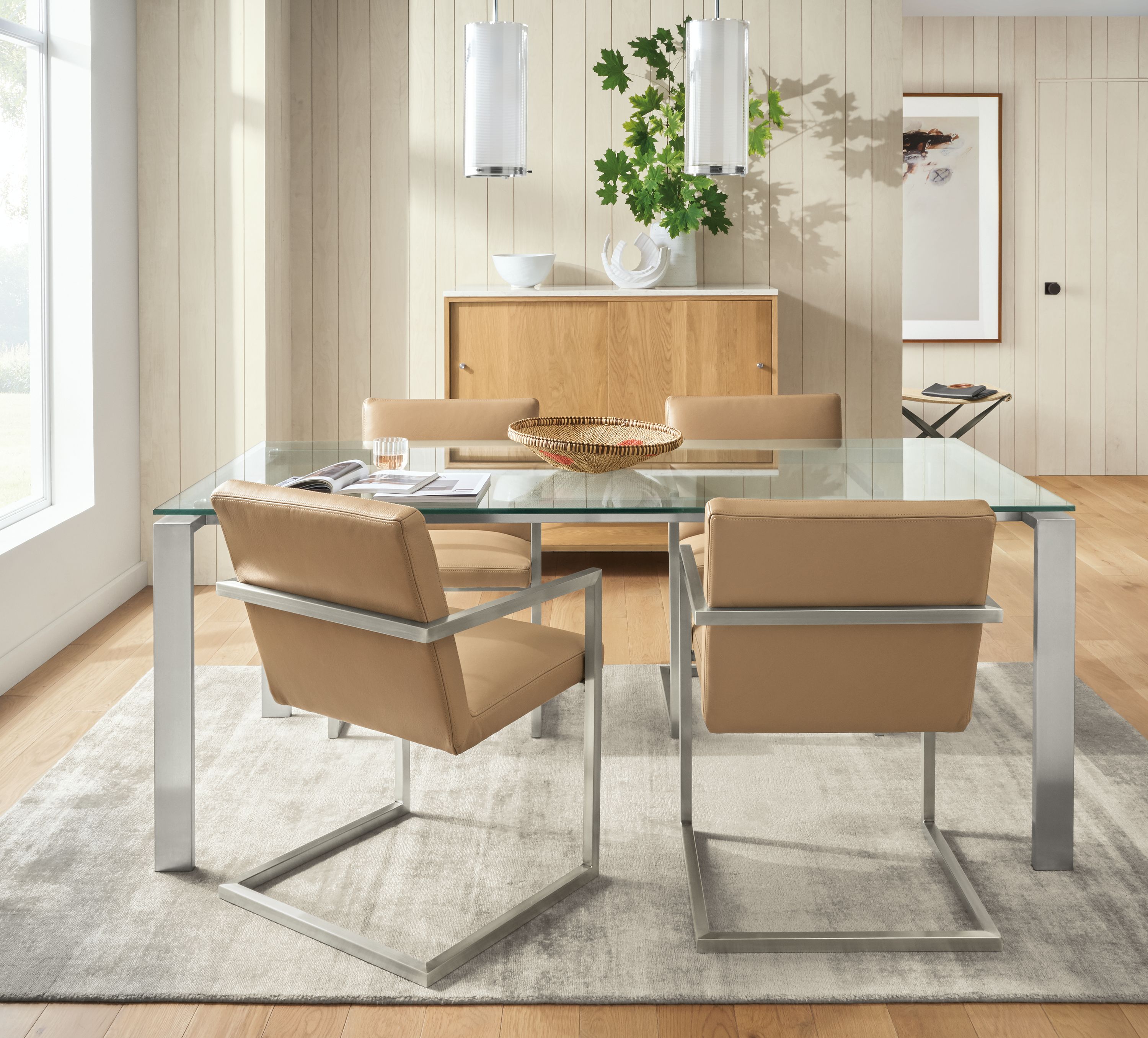 Detail of Rand table with glass top and stainless steel base with Lira leather arm chairs.