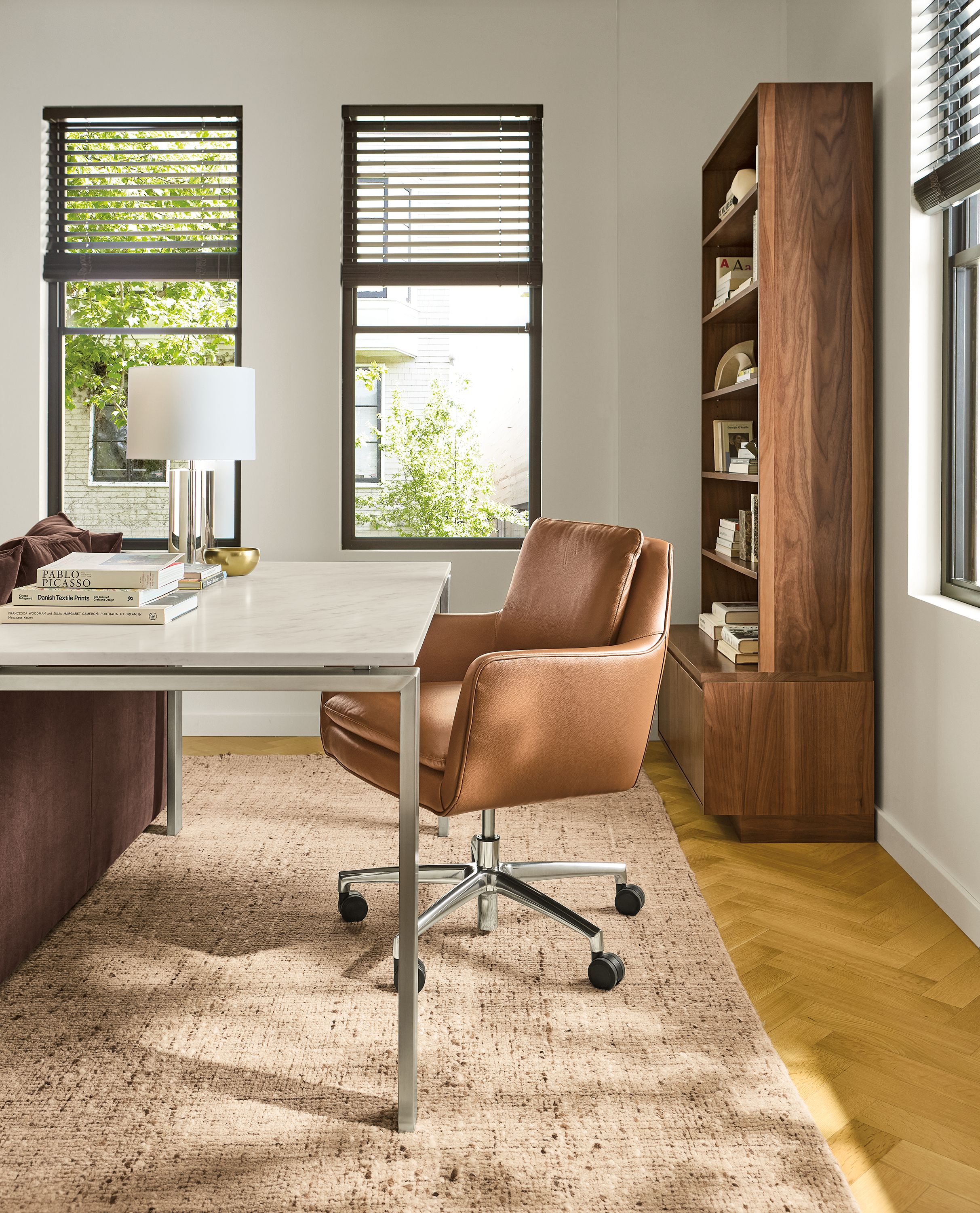 Home office with Rand table in stainless with marbled warm white quartz top and Penny office chair in pesaro cognac leather.