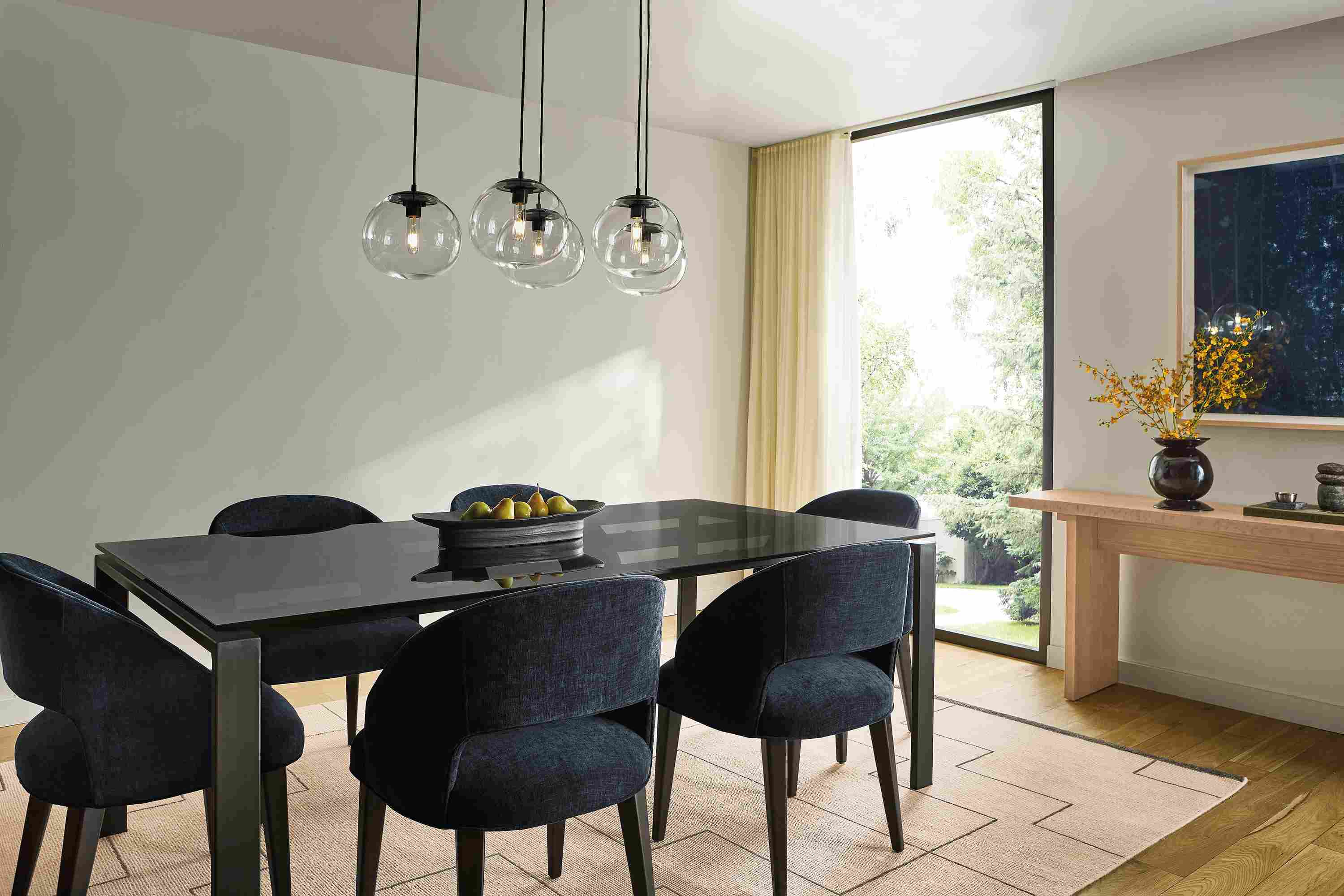 Dining Room with Rand 78-wide table in smoked glass, 6 Esme chairs in Mori Navy and Navi 8 by 10 rug in Ivory/Black.