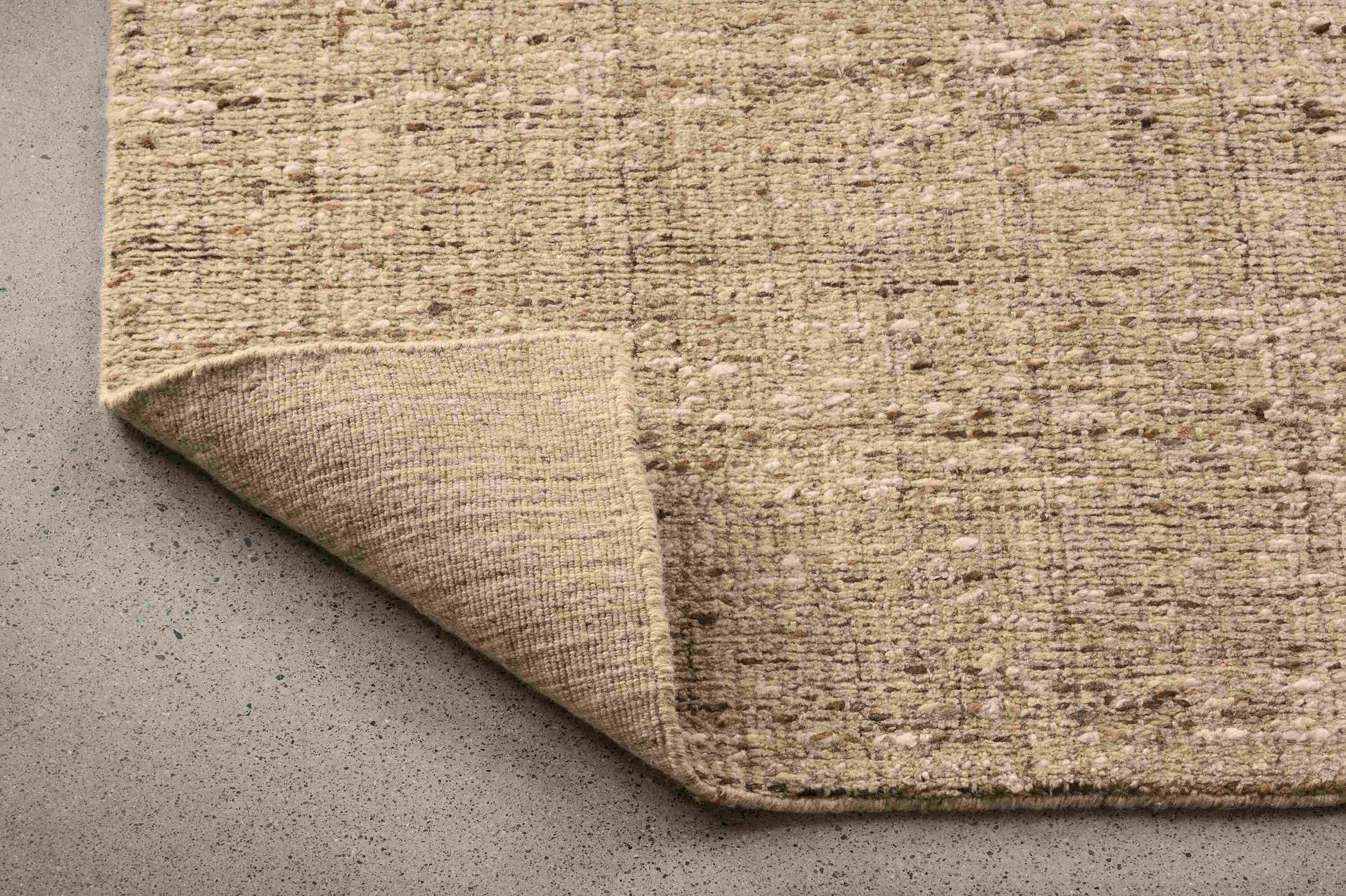 Detail of a Ravani 8 by 10 rug in oatmeal with corner folded up to show underside of rug.