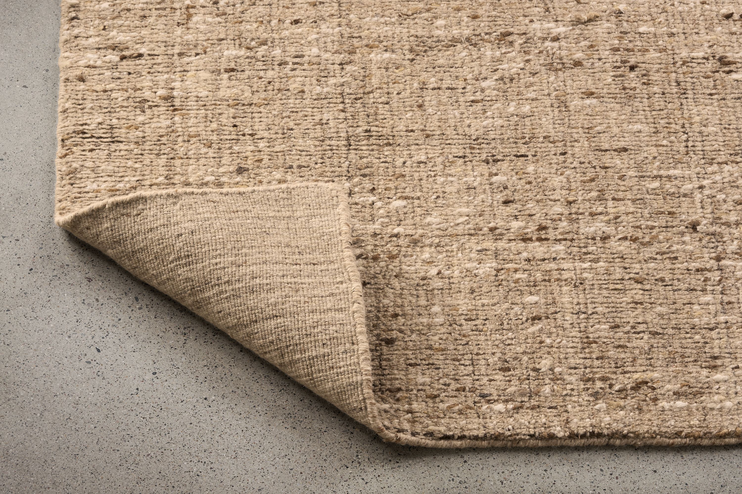 Detail of a Ravani 8 by 10 rug in oatmeal with corner folded up to show underside of rug.