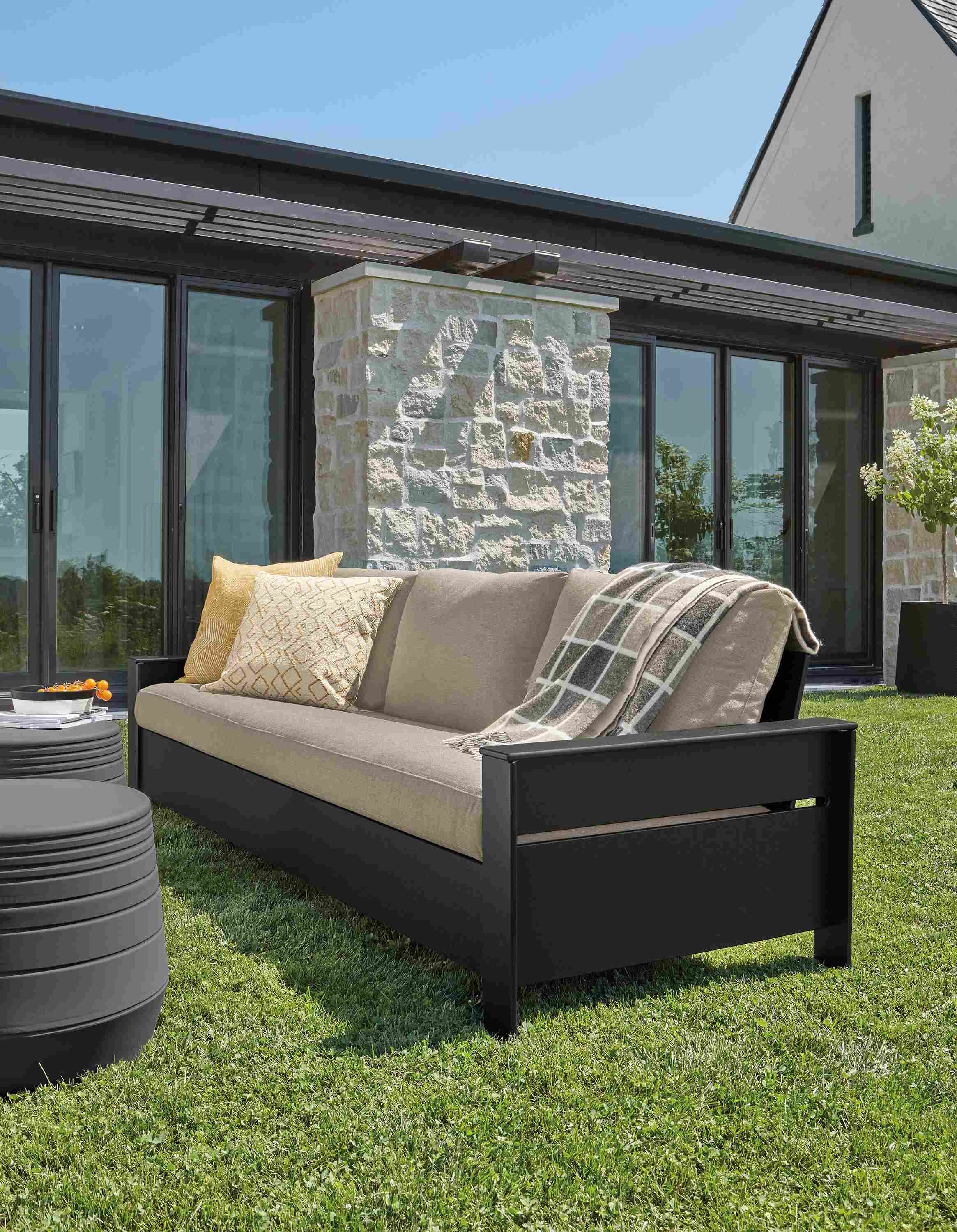 Rayo 92-inch outdoor sofa in black with Pelham charcoal cushions and two cusp round stools in grey.
