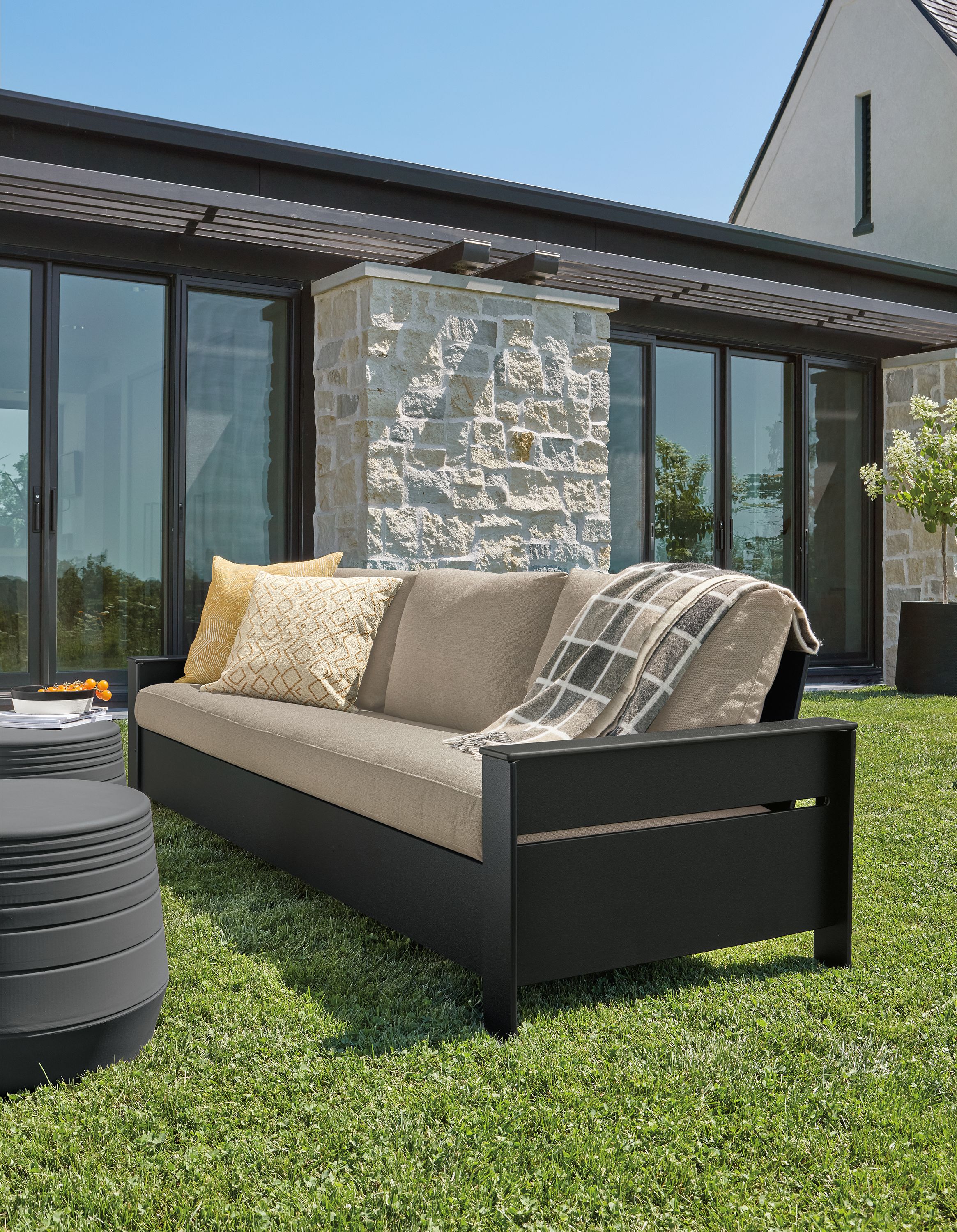 Rayo 92-inch outdoor sofa in black with Pelham charcoal cushions and two cusp round stools in grey.