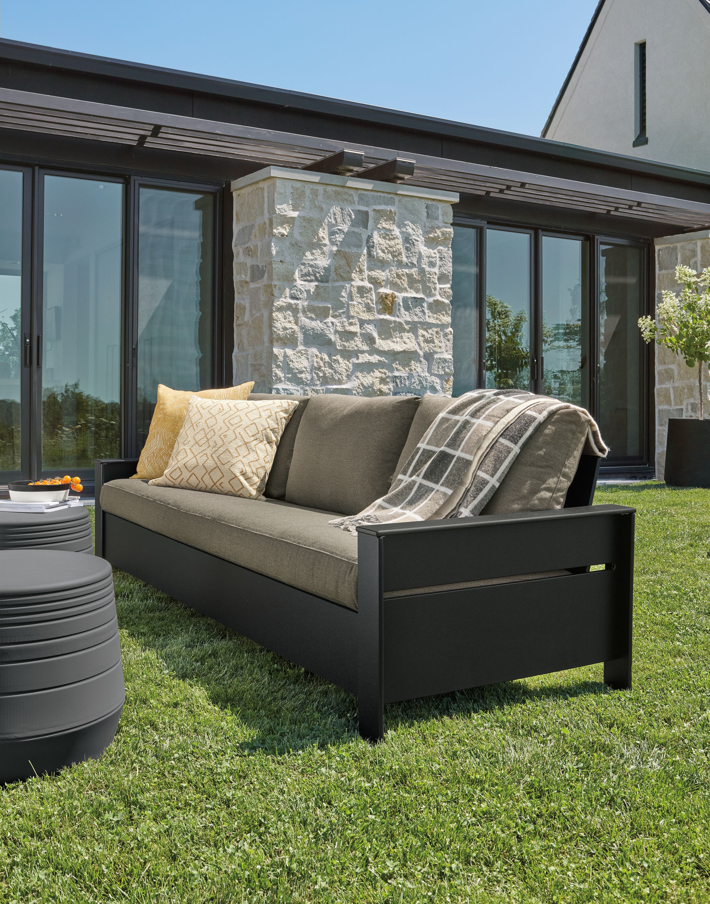 Rayo 92-inch outdoor sofa in black with Pelham charcoal cushions and two cusp round stools in umber.