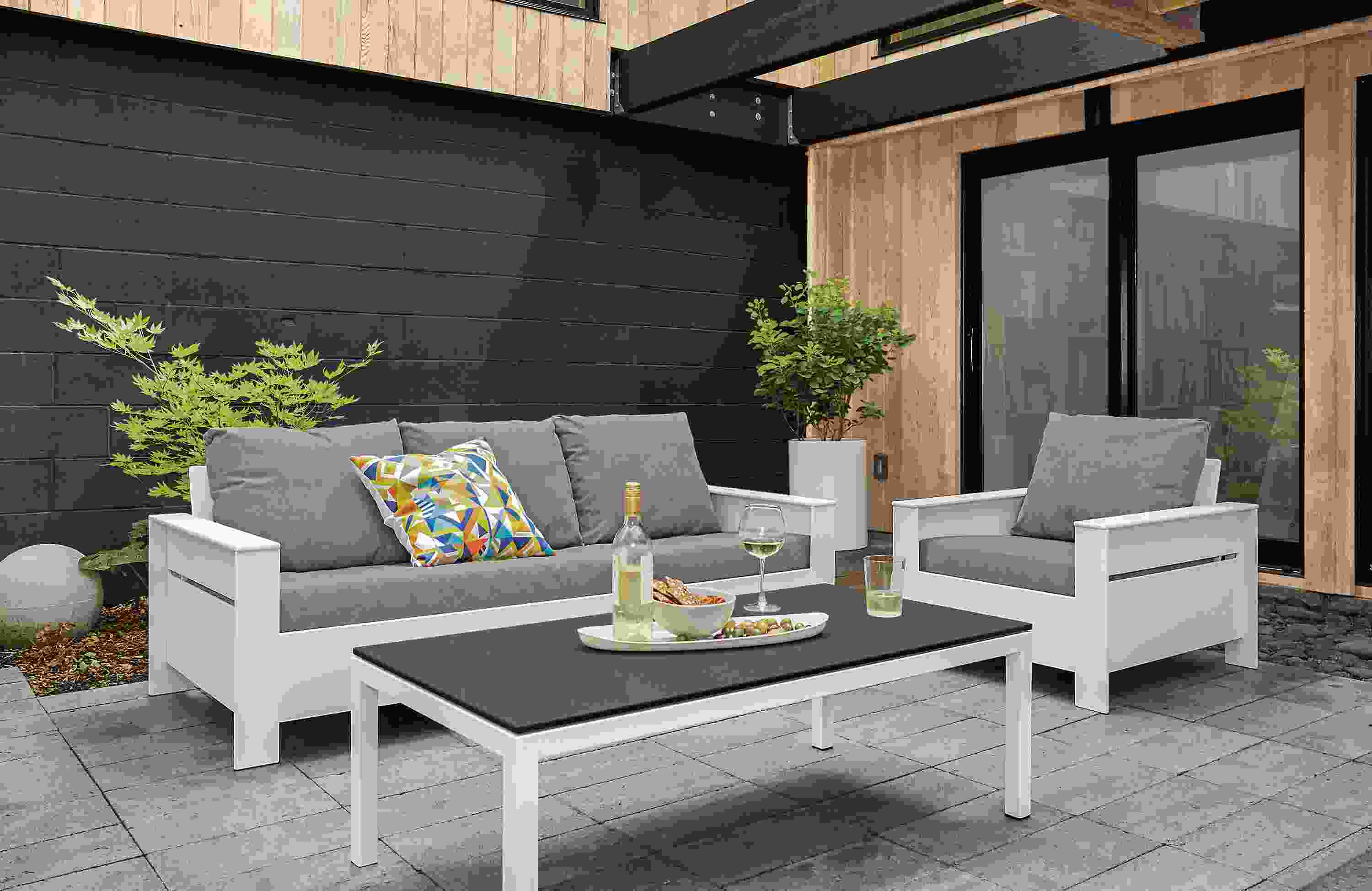 Patio with Rayo sofa and chair in white with Sunbrella Canvas slate cushions and Pratt cocktail table in white.