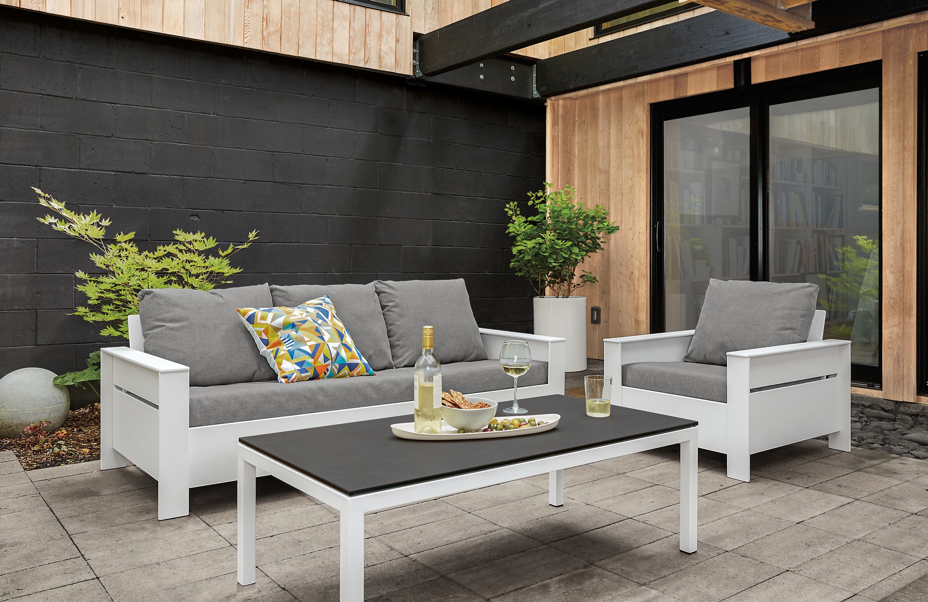 Patio with Rayo sofa and chair in white with Sunbrella Canvas slate cushions and Pratt cocktail table in white.