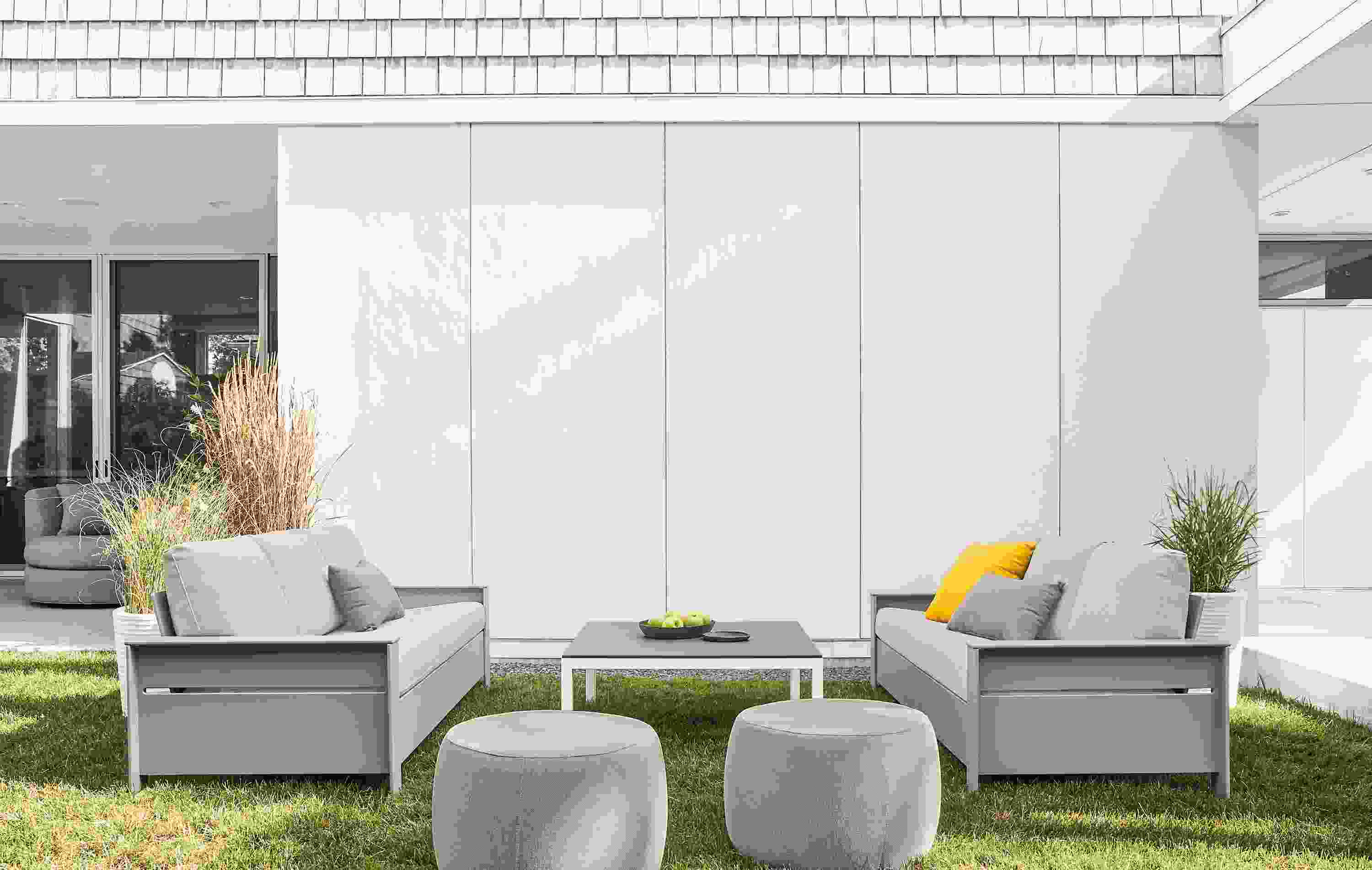 Two Rayo sofas Light Grey with Mist Grey cushions and 2 Boyd ottomans in Mist Grey in lawn.