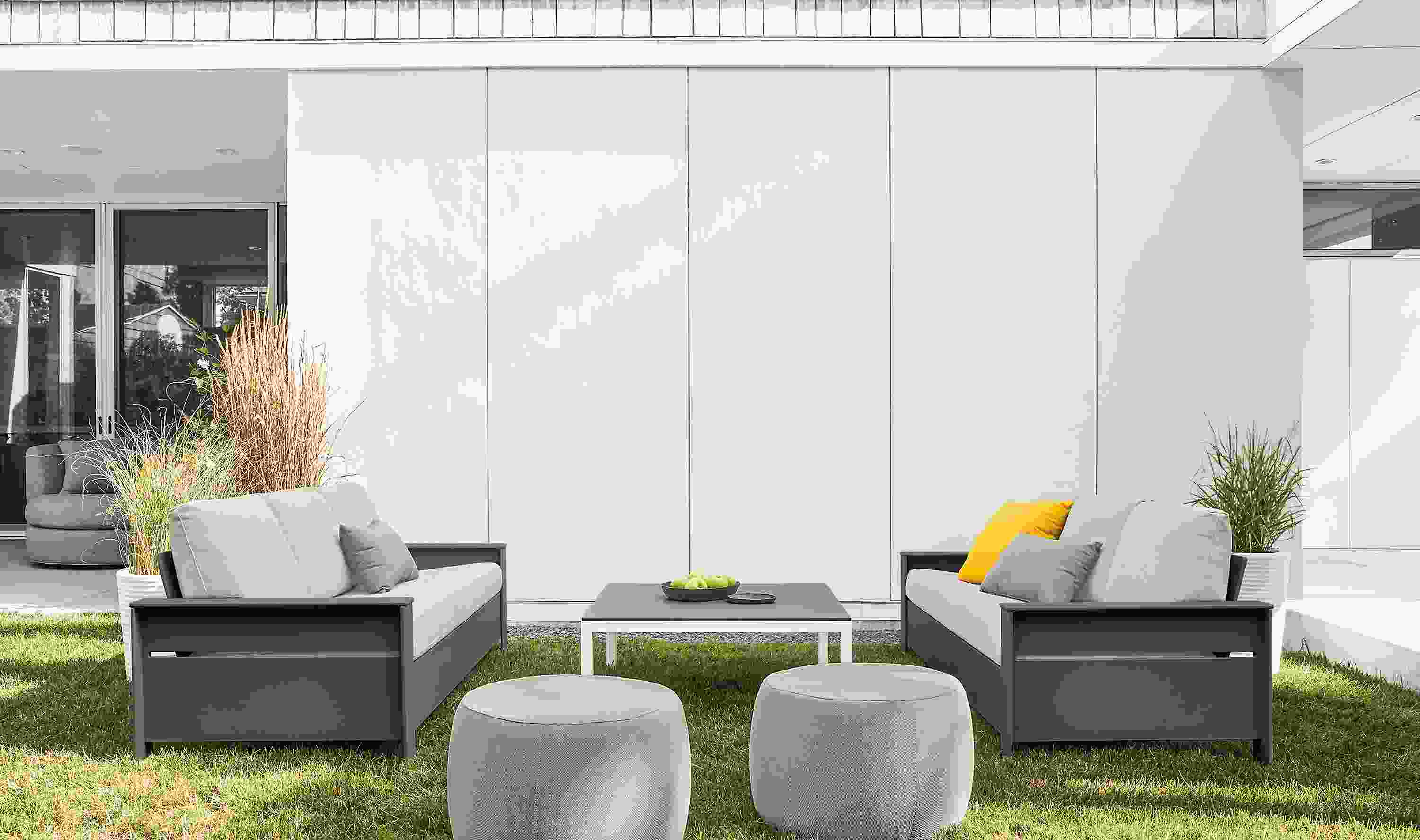 Lawn seating area with 2 Rayo sofas in Mist Grey and Grey HDPE and 2 Boyd ottomans in Mist Grey.