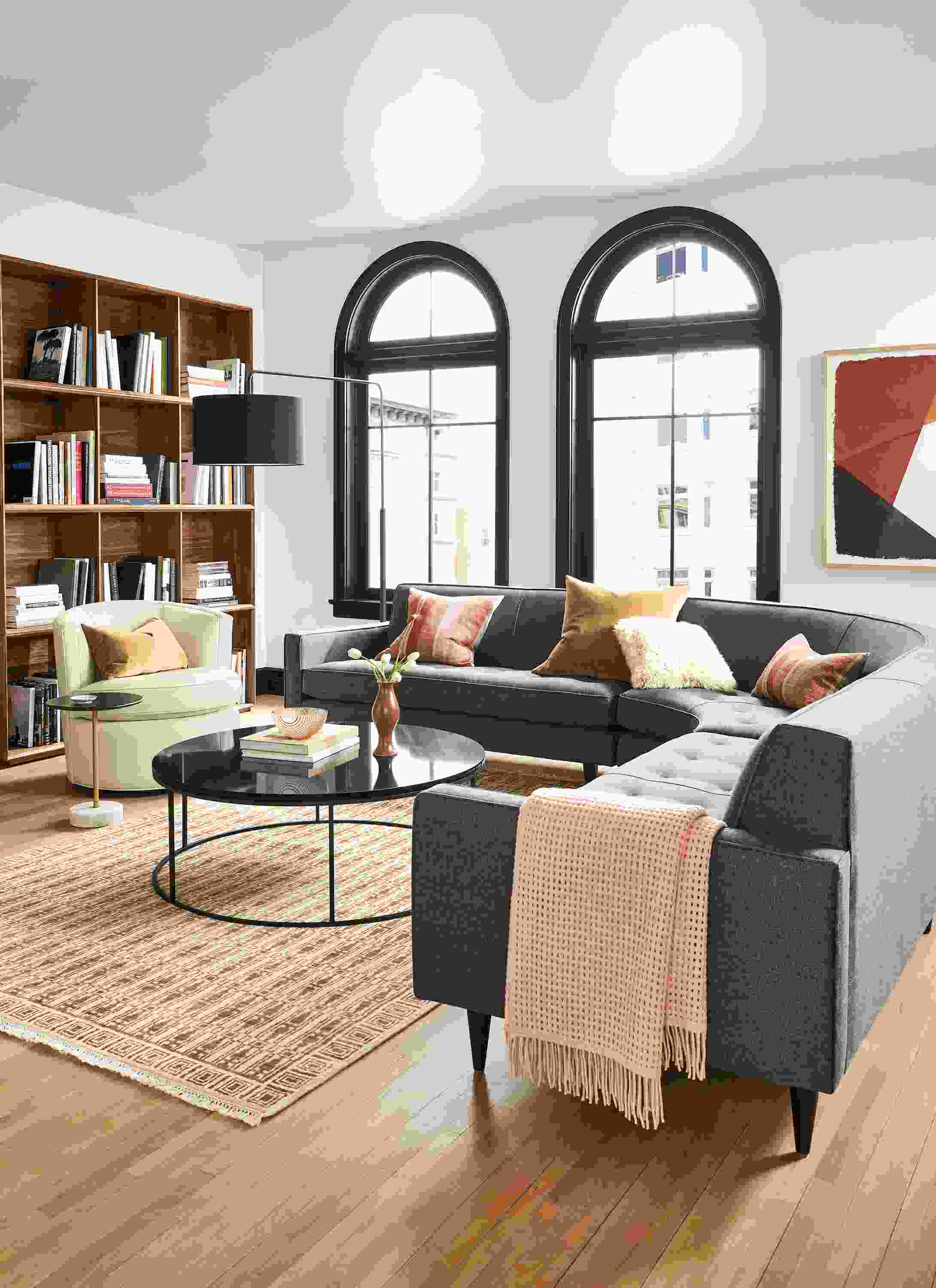 Living room with curved Reese sectional in Gino Charcoal fabric and Otis swivel chair in Urbino Ivory leather.