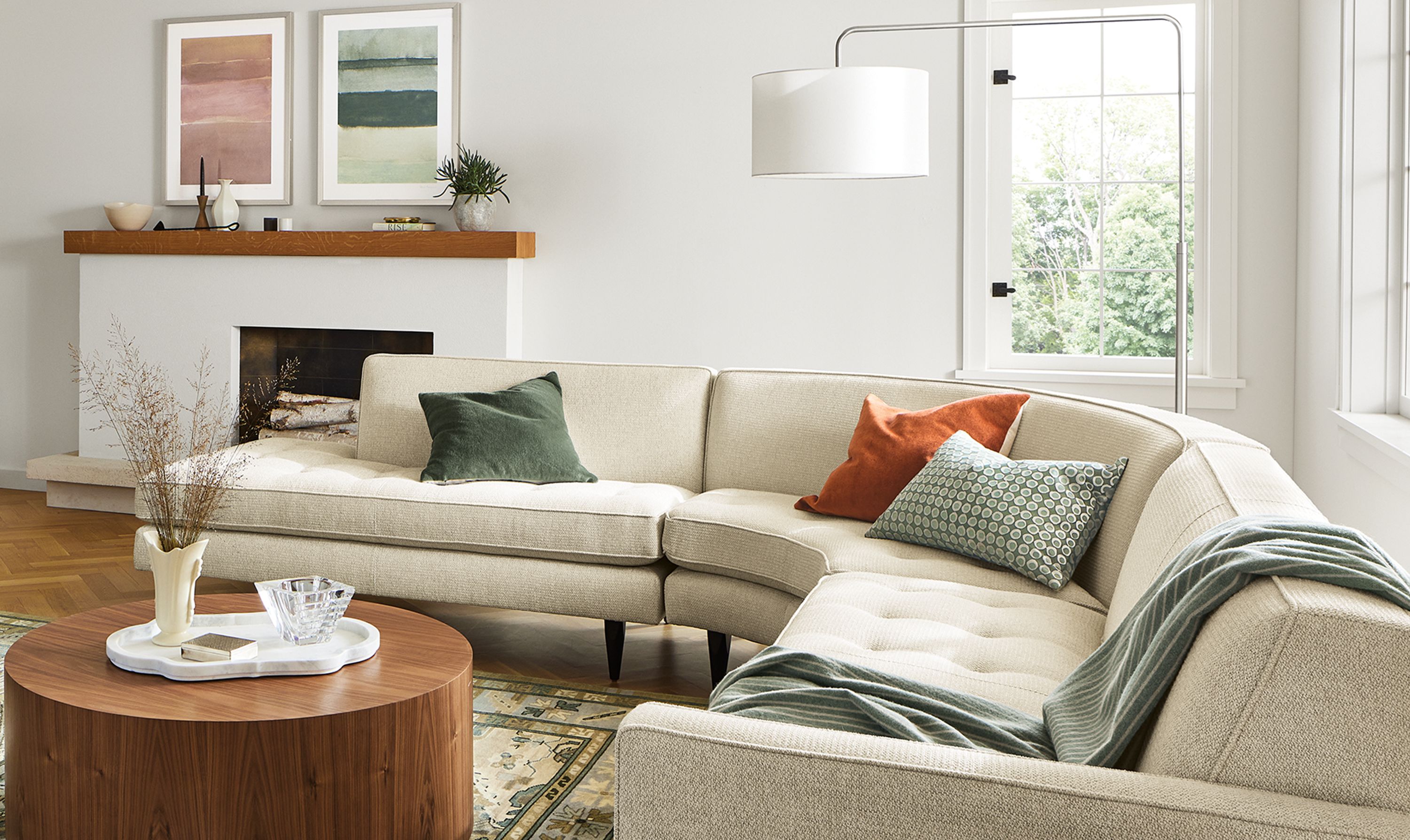 Living room with Reese 115-wide 3-piece curved sectional in Orla Ivory, Xavier chair in Palermo charcoal leather.