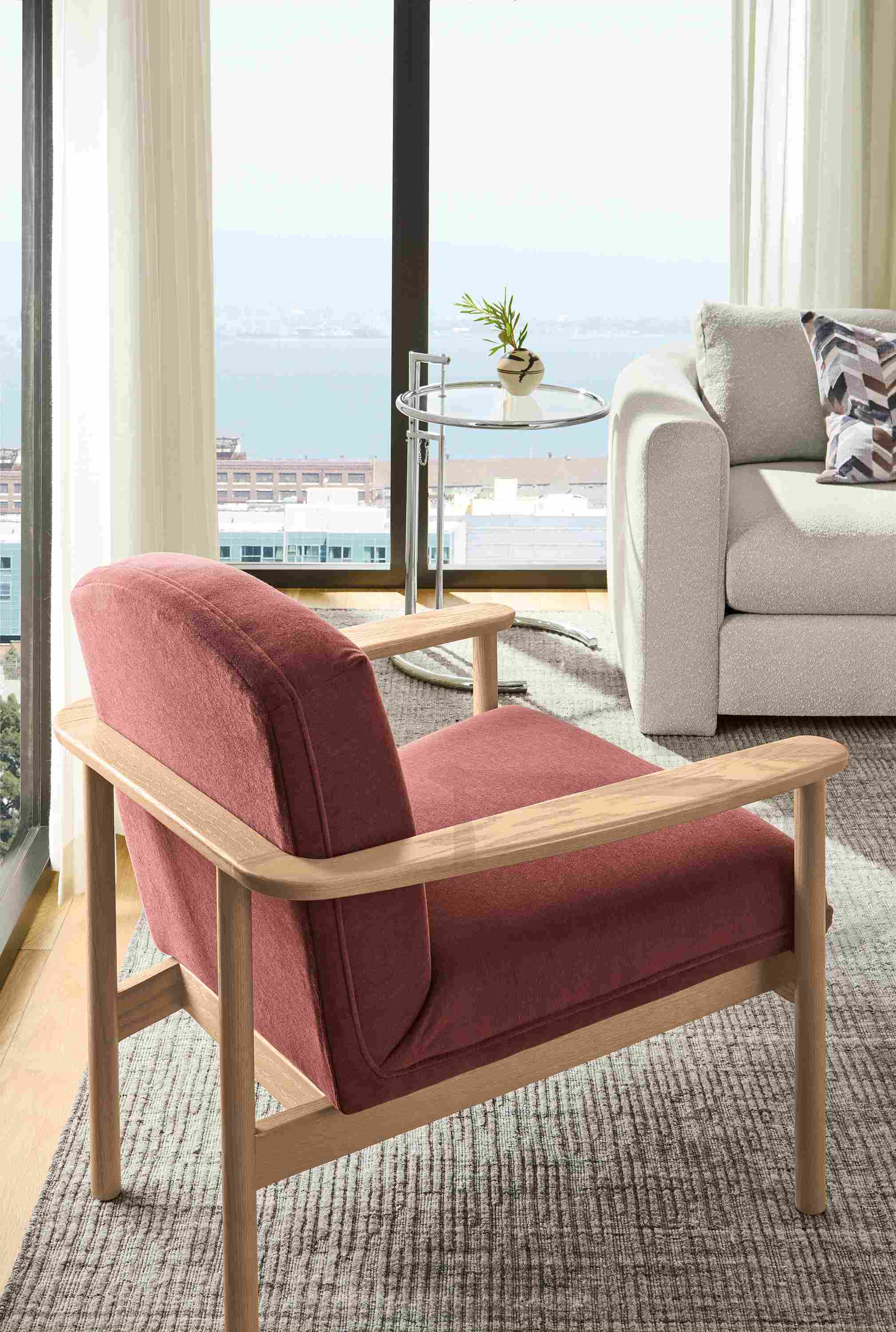 High-rise apartment living room corner with Renew chair in Terra Clay and Eileen Gray 20-diameter coffee table in chrome.