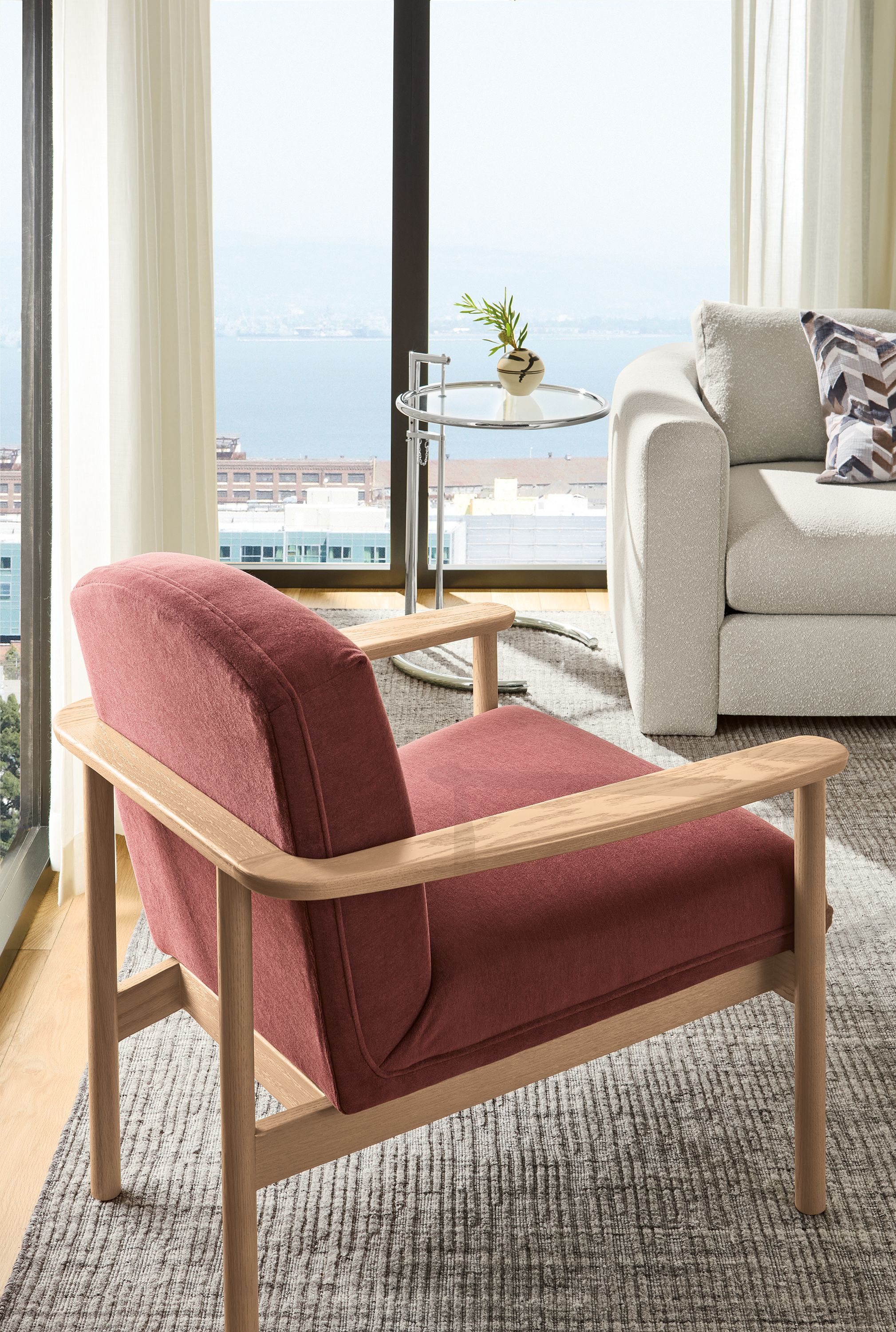 High-rise apartment living room corner with Renew chair in Terra Clay and Eileen Gray 20-diameter coffee table in chrome.