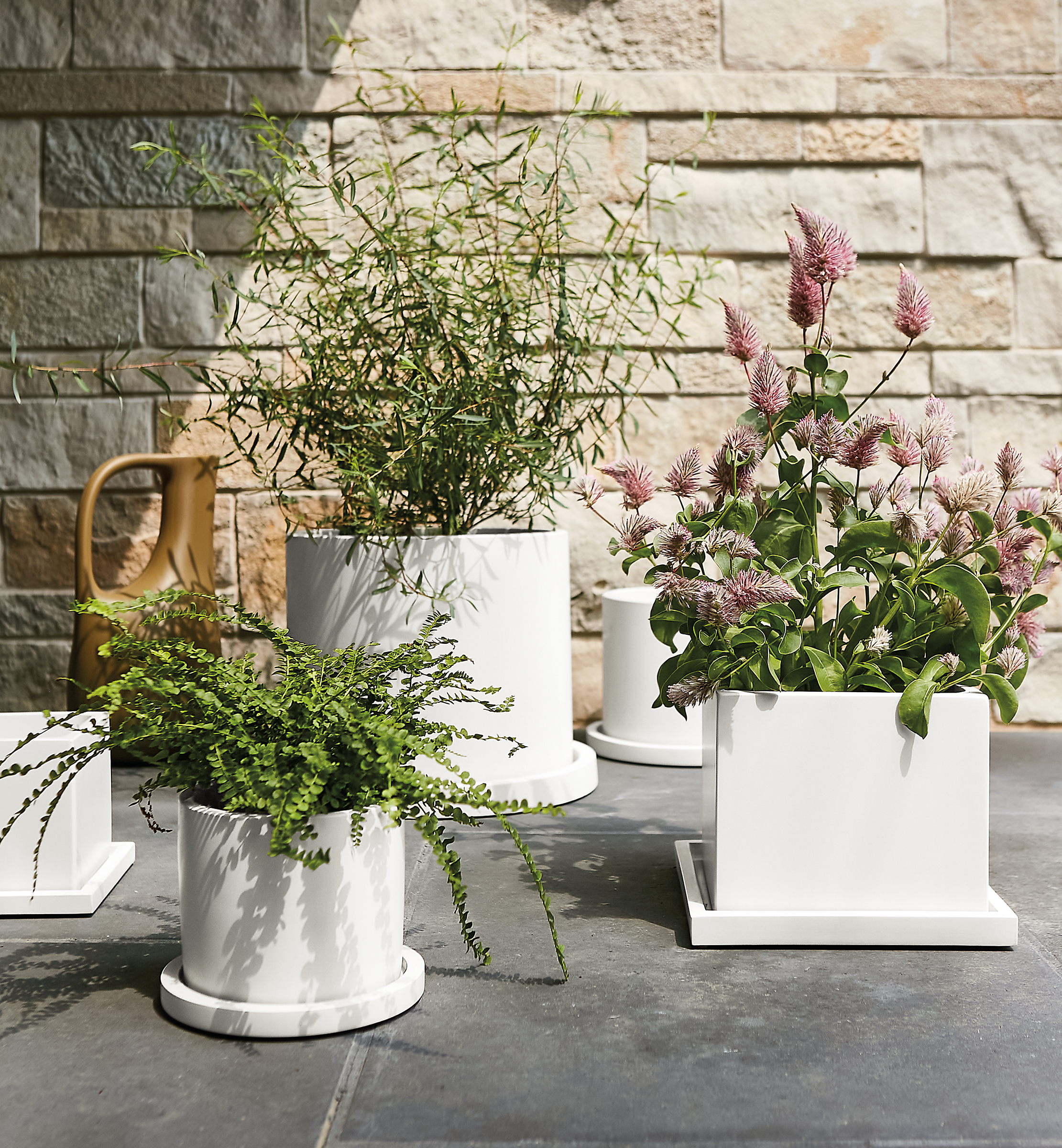 several renga planters in white on stone walkway outdoors.