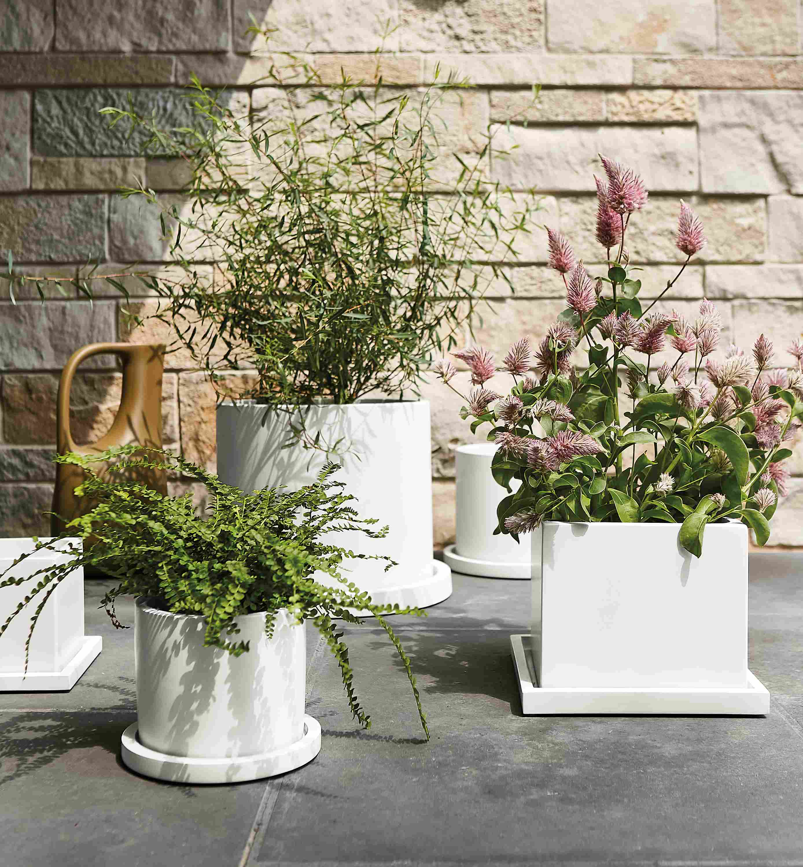 Several renga planters in white on stone walkway outdoors.