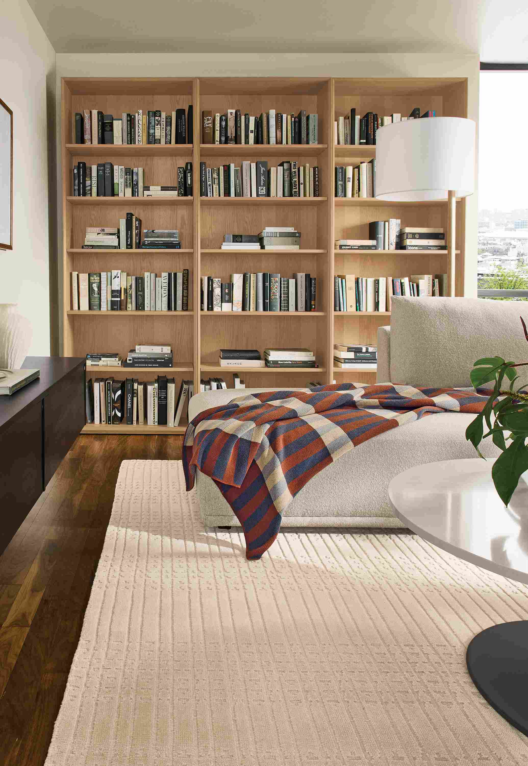 Living room with 3-Rollins bookcases in rye on red oak, Fia sofa in Conley Natural and Bria rug in ivory.