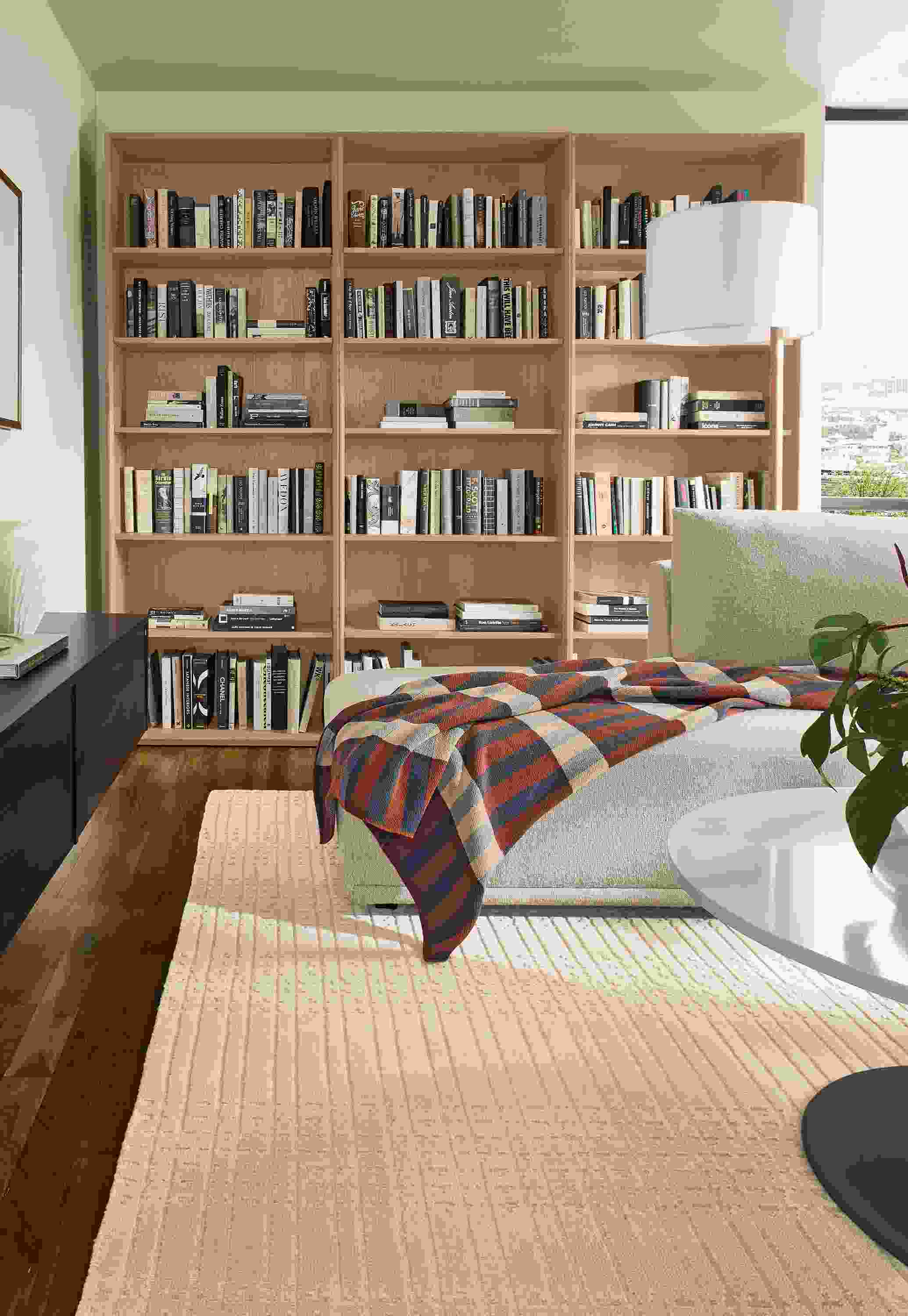 Living room with 3-Rollins bookcases in rye on red oak, Fia sofa in Conley Natural and Bria rug in ivory.