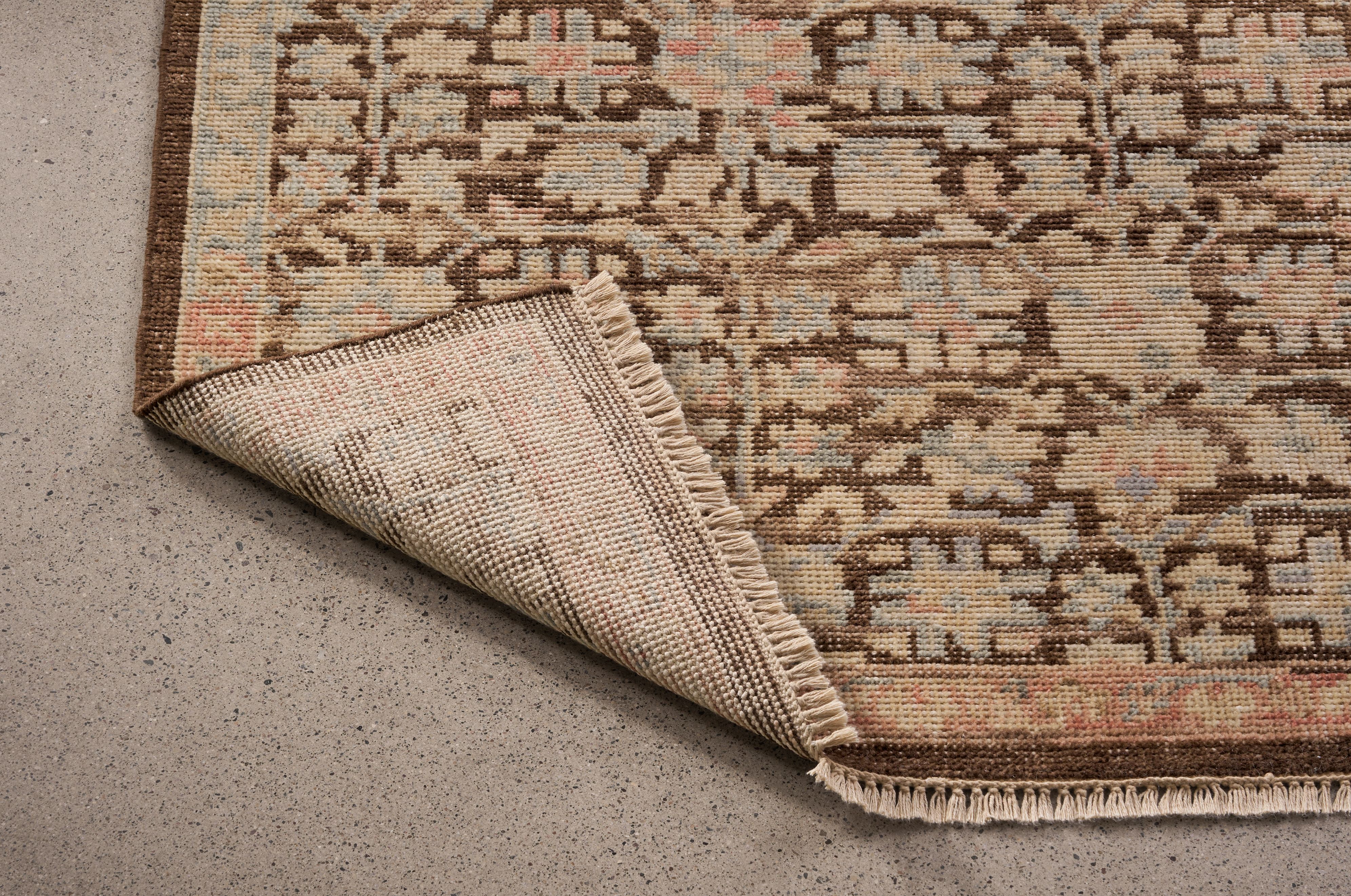 Detail of Rosalie 8 by 10 rug in petal shown with corner flipped up to show underside of rug.
