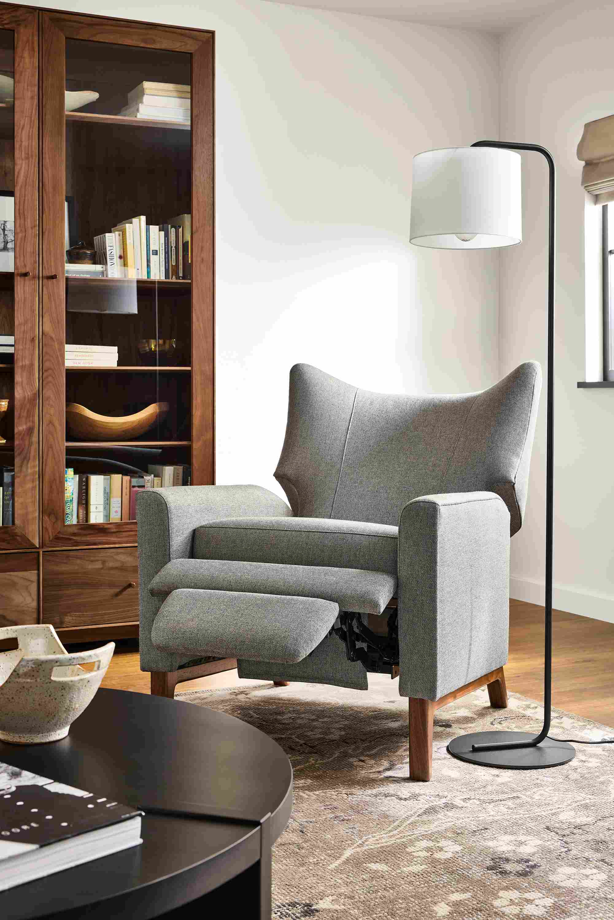 Living room with detail of roth recliner in sumner graphite shown in reclining position and hanover round coffee table in charcoal.