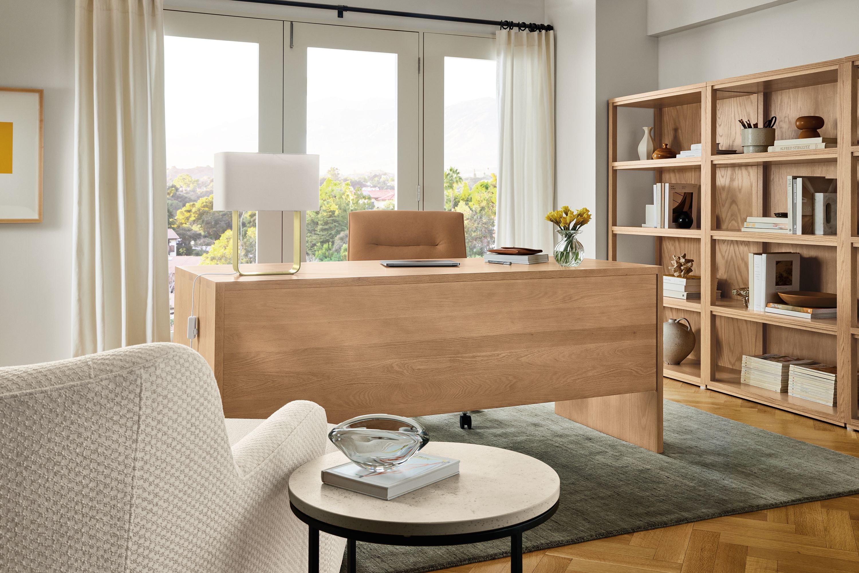 Office with Rowan desk with privacy panel in rye on red oak, Jude office chair in Laino Camel leather and Nomad rug in olive.