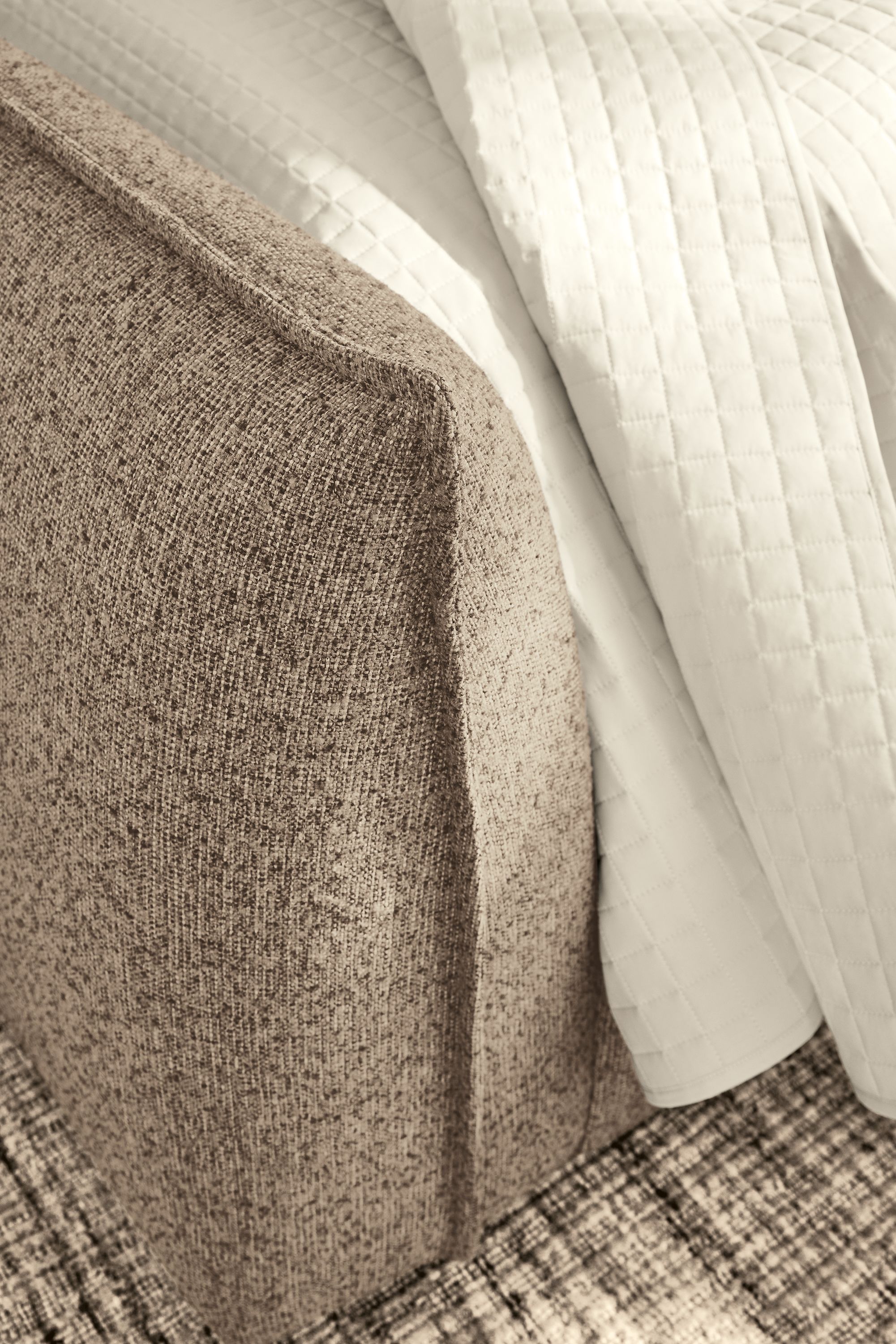 Detail of footboard on a Rue king bed in Conley Mink fabric and Signature percale quilted coverlet in ecru.