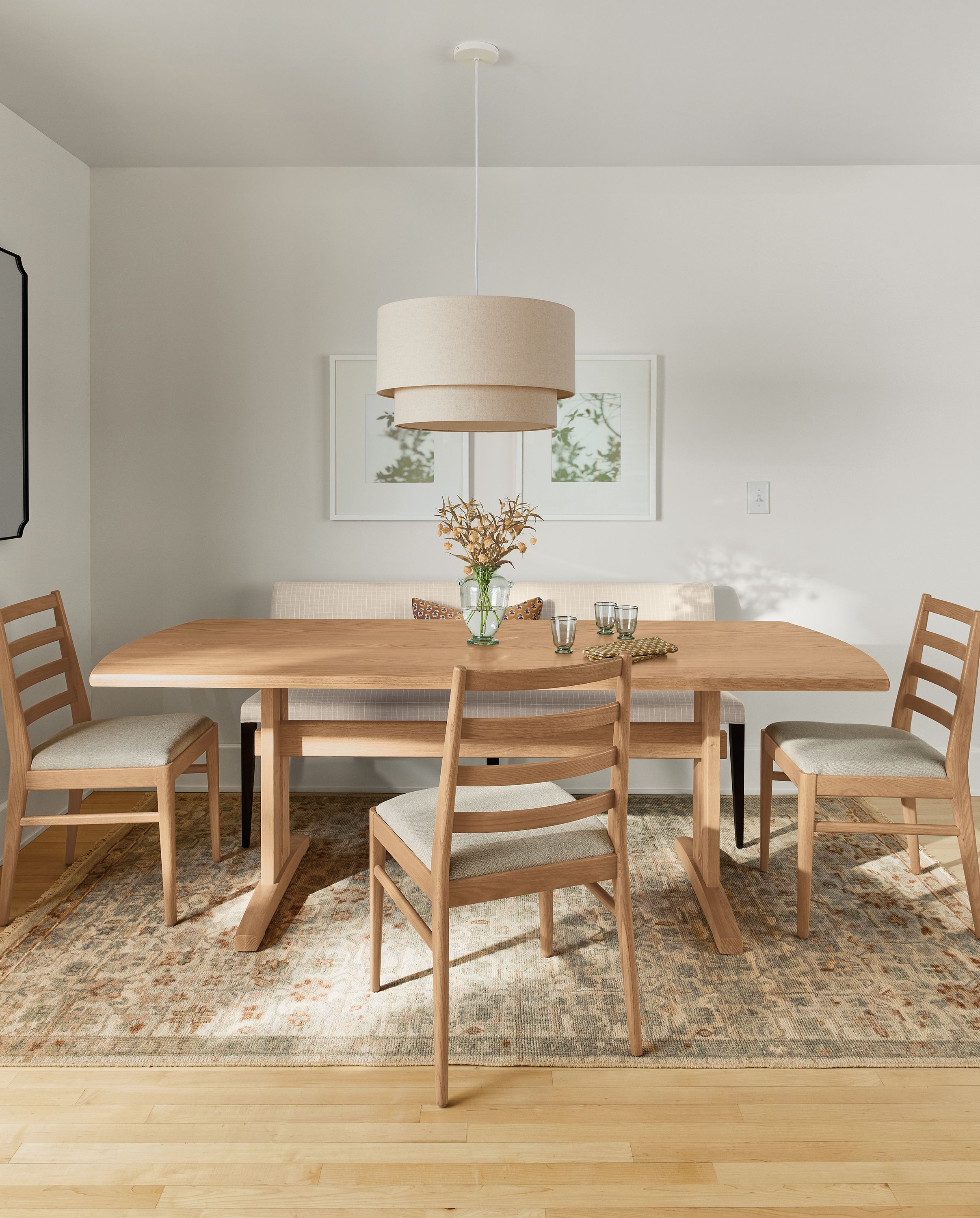 Dining room with Salem 84-wide table in rye on red oak, Ava banquette in prado natural and Rosalie rug in frost.