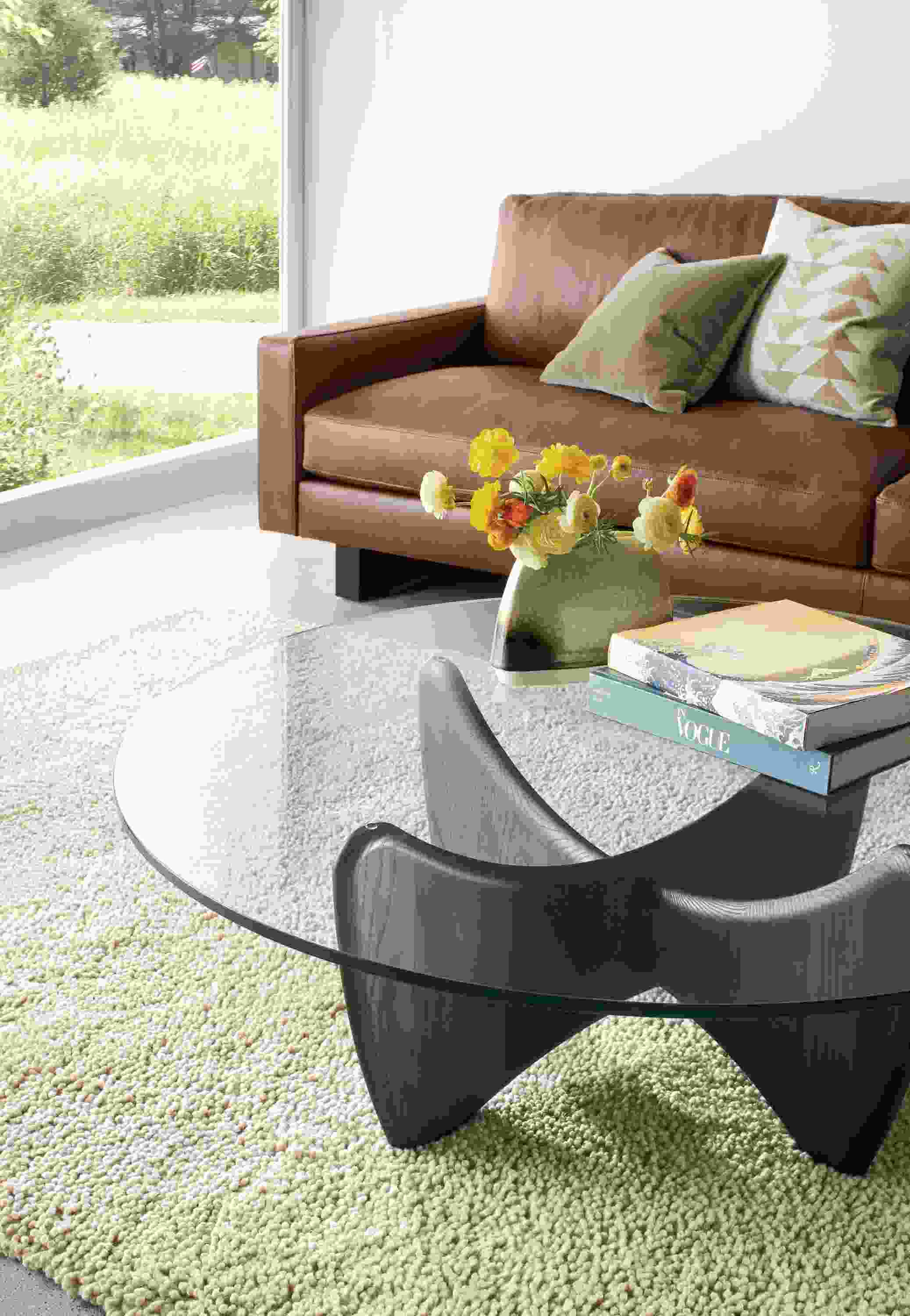 Detail of Sanders round cocktail table in charcoal and clear glass in living room.