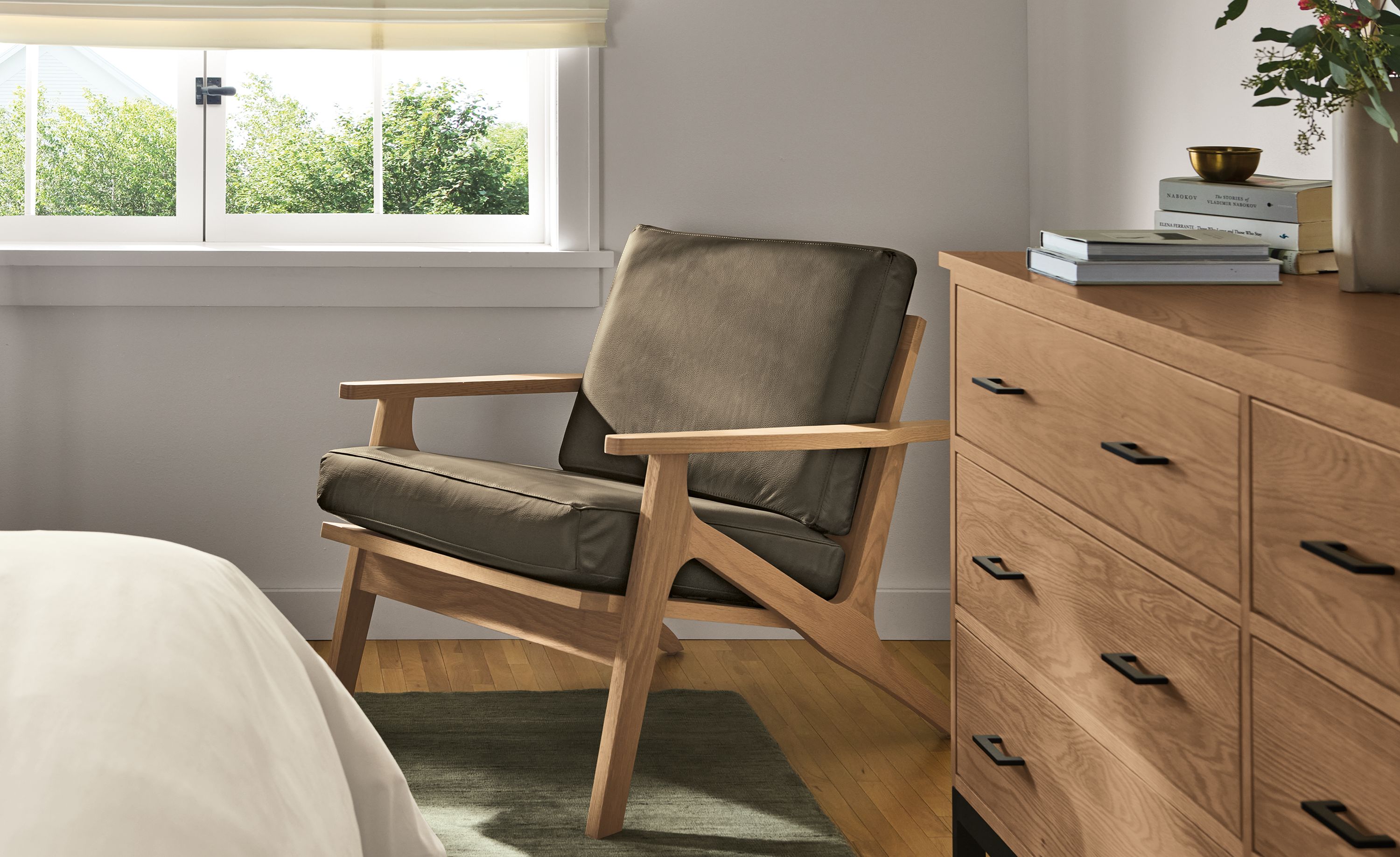 Bedroom with Sanna chair in Pesaro Mink Leather and rye on red oak and Nomad rug in Olive.