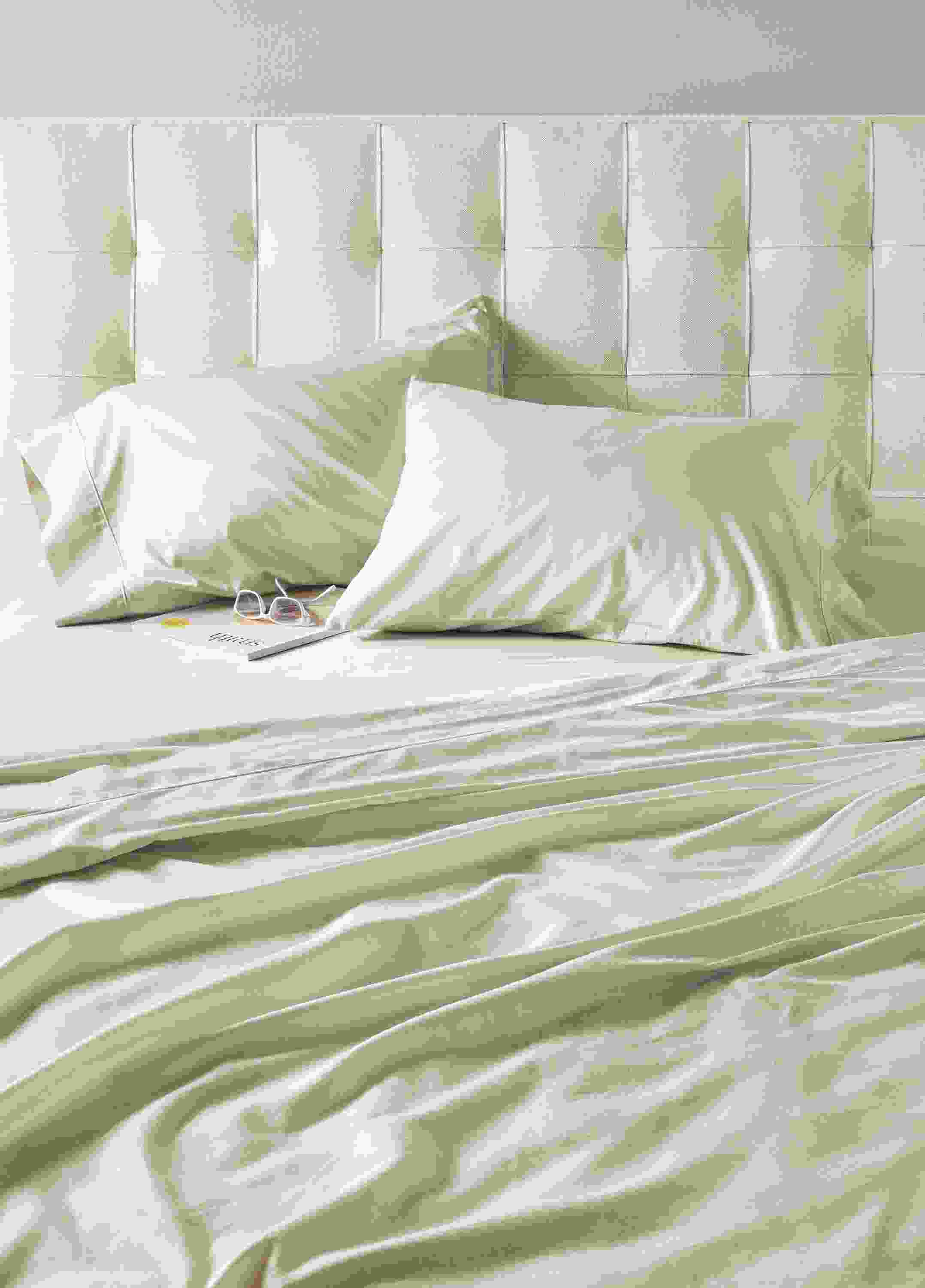 Detailed shot of tailored sateen sheets and pillowcases in Ecru.
