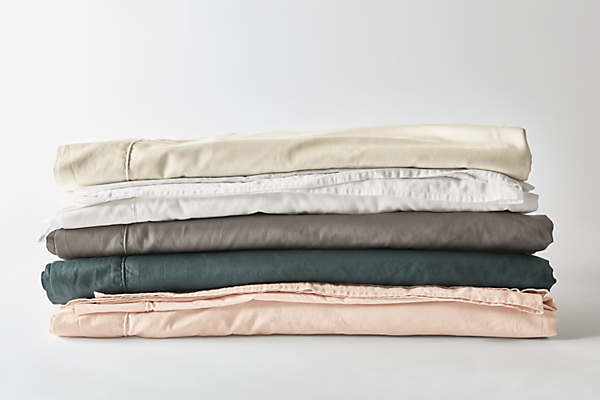 Detailed image of tailored sateen sheets in blush, dark slate, charcoal, white and ecru.