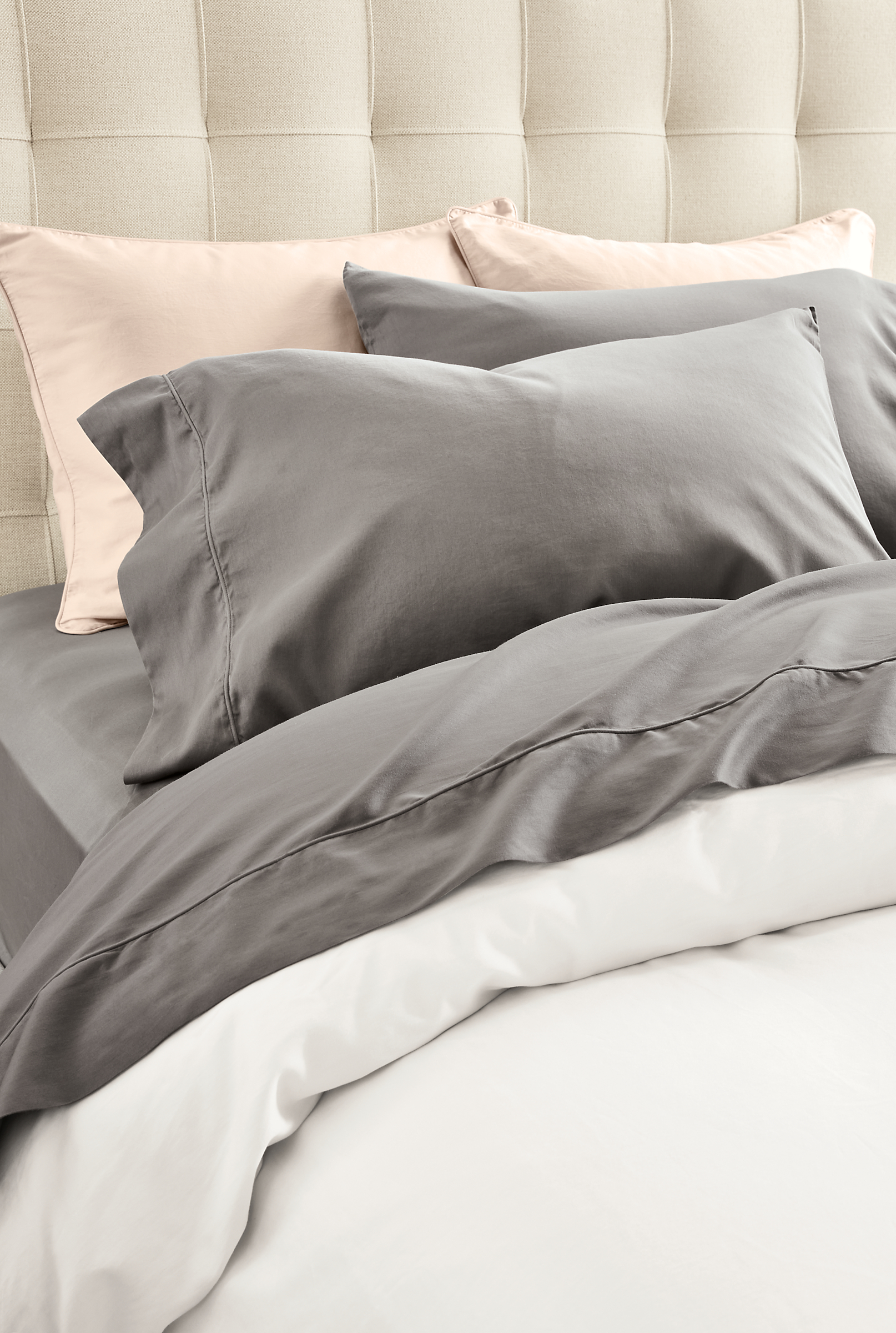 Detailed image of tailored sateen sheets in charcoal and  pillowcases in charcoal and blush.