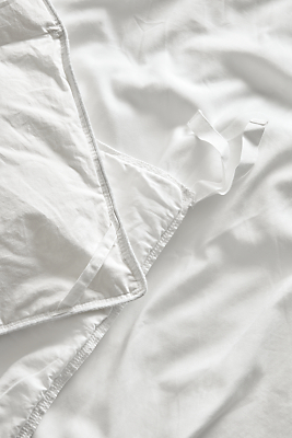 Detailed shot of tailored sateen sheets and duvet cover in white.