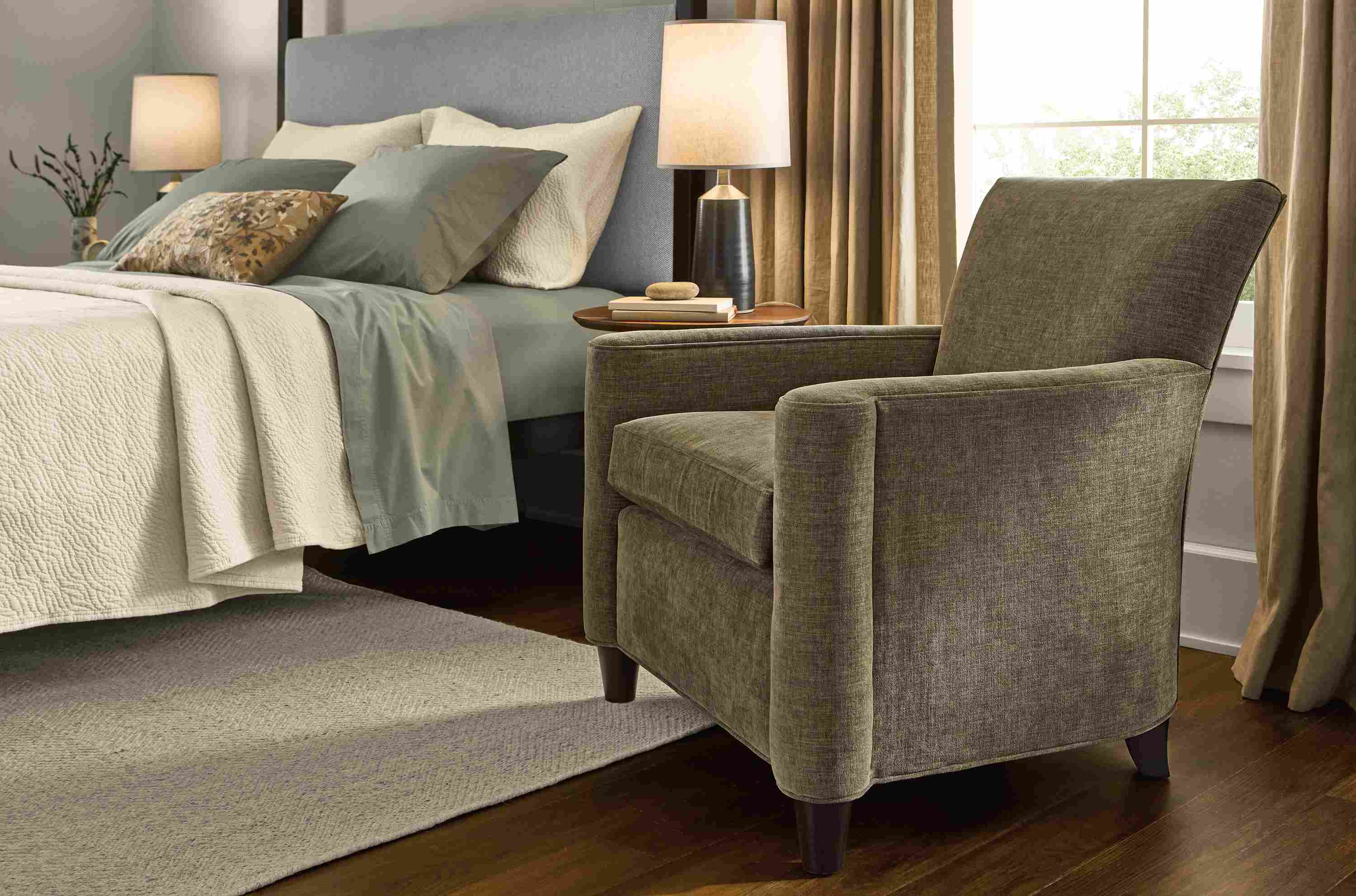 Bedroom with a Savoy chair in Mori Olive next to an Adams end table in walnut and Architecture bed in Derry Cement.