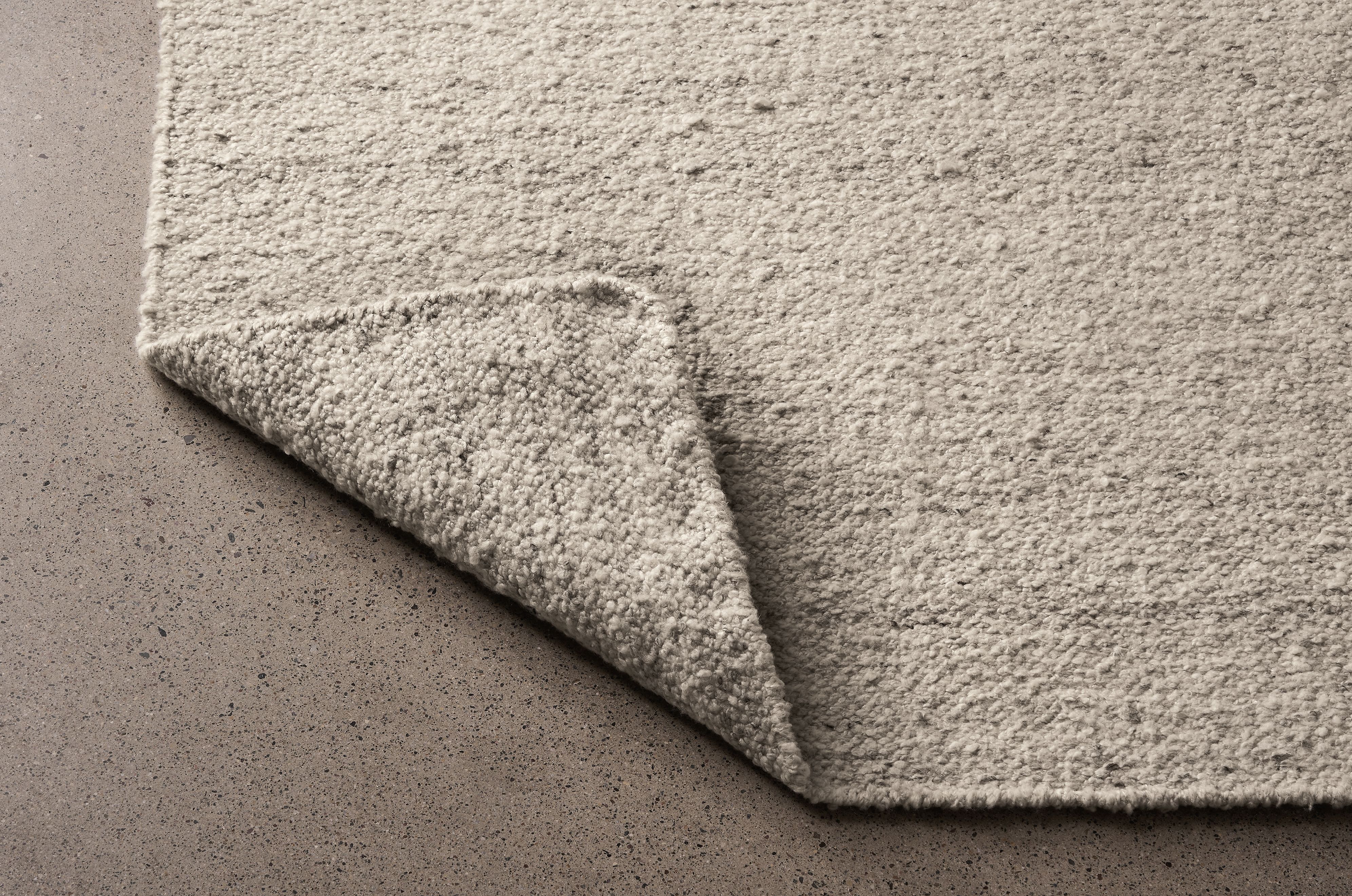 Detail of Sefton 8 by 10 rug in cement shown with corner flipped up to show underside of rug.