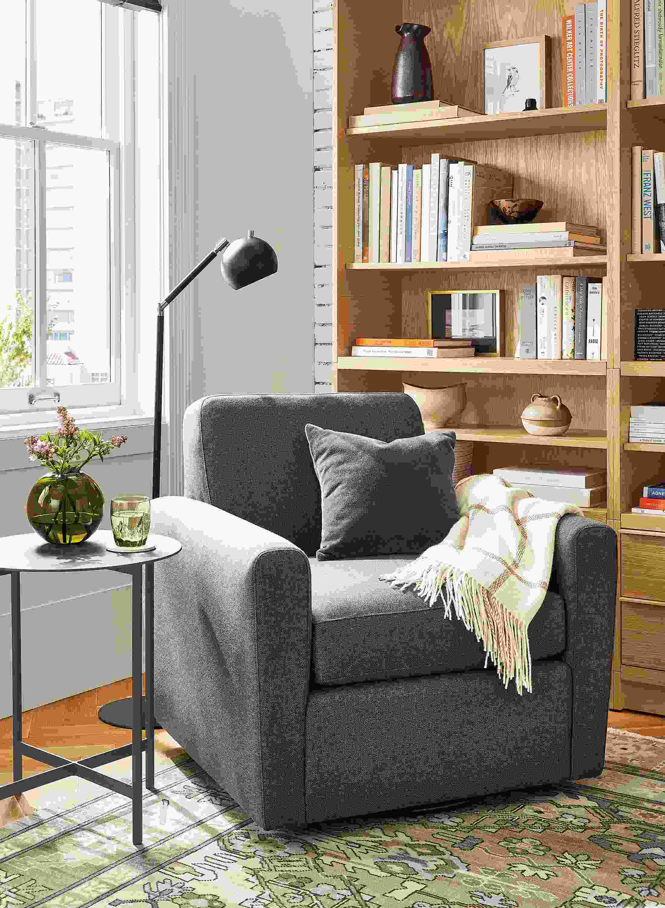 Living room with Seth swivel chair in Gino Charcoal, Taylor bookcases, Camber floor lamp.