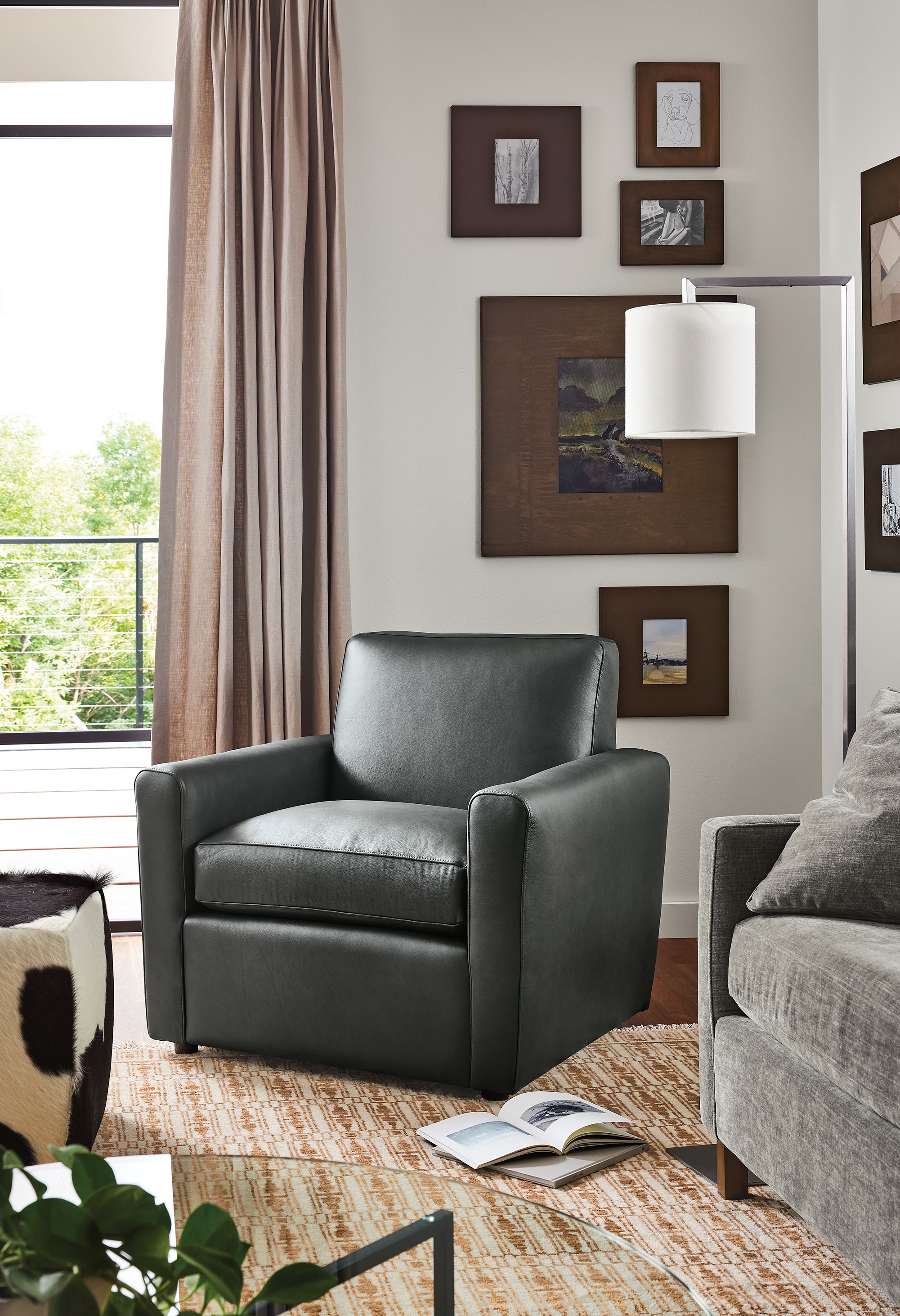 Living room with Seth chair in Laino Black, Tulum rug in copper, and Lind cowhide ottoman in black.