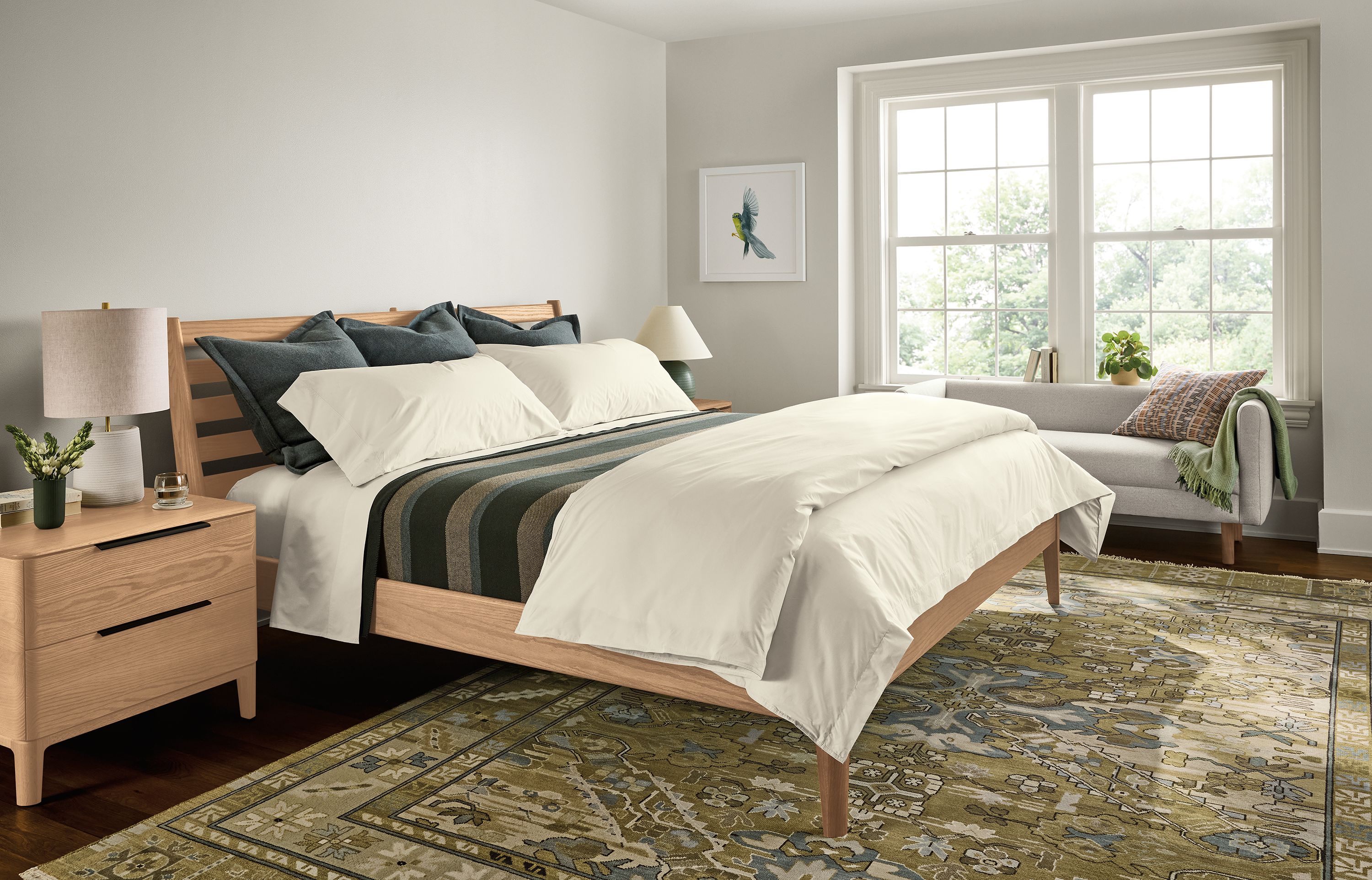 A large, bright bedroom with Silas bed and 2 kingston nightstands in rye on red oak and Kayseri rug in moss.