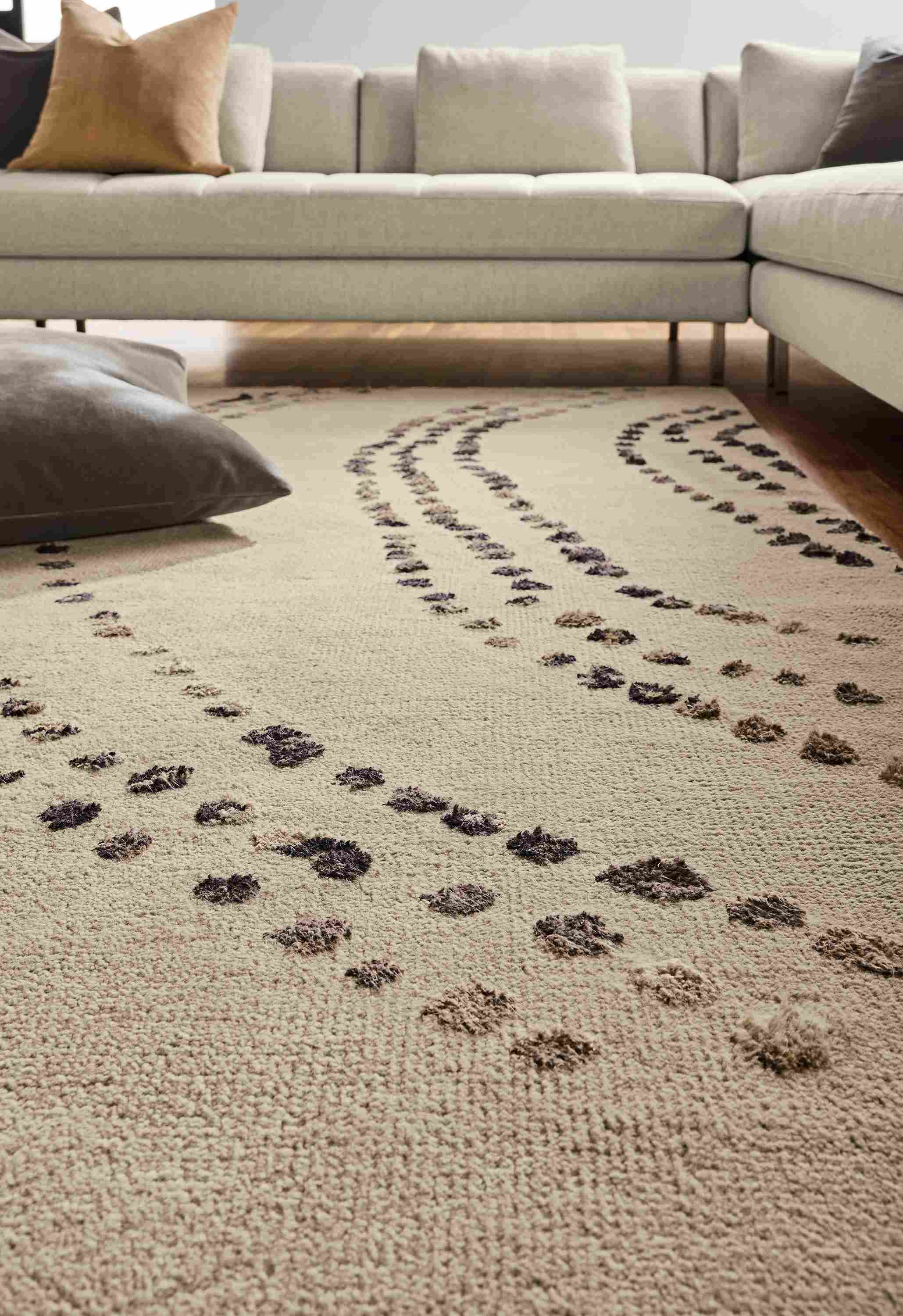 Low-angle view of Sitara 8 by 10 rug in pewter, Lloyd sectional in Sumner Linen and Redding pillow in otter.