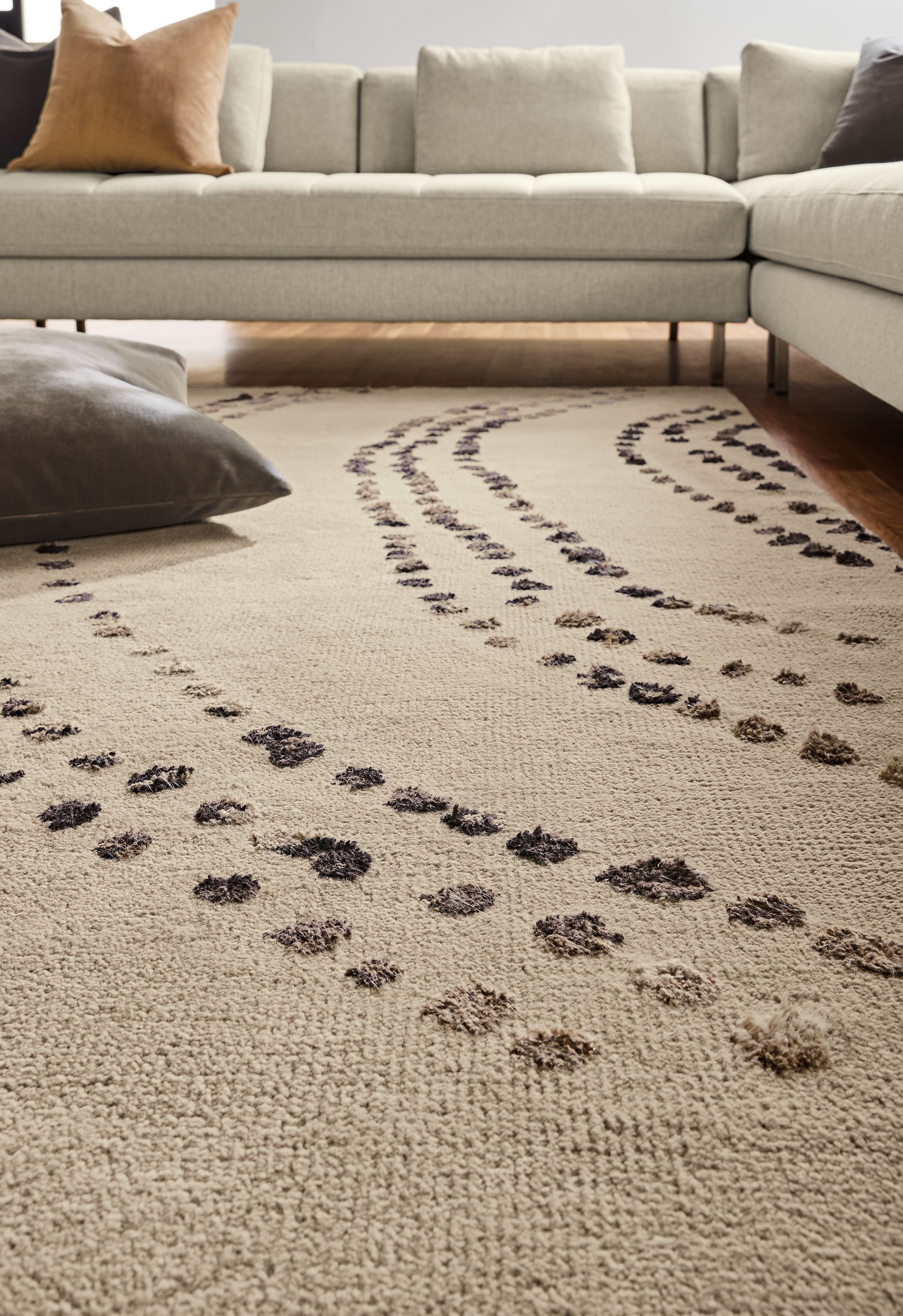 Low-angle view of Sitara 8 by 10 rug in pewter, Lloyd sectional in Sumner Linen and Redding pillow in otter.