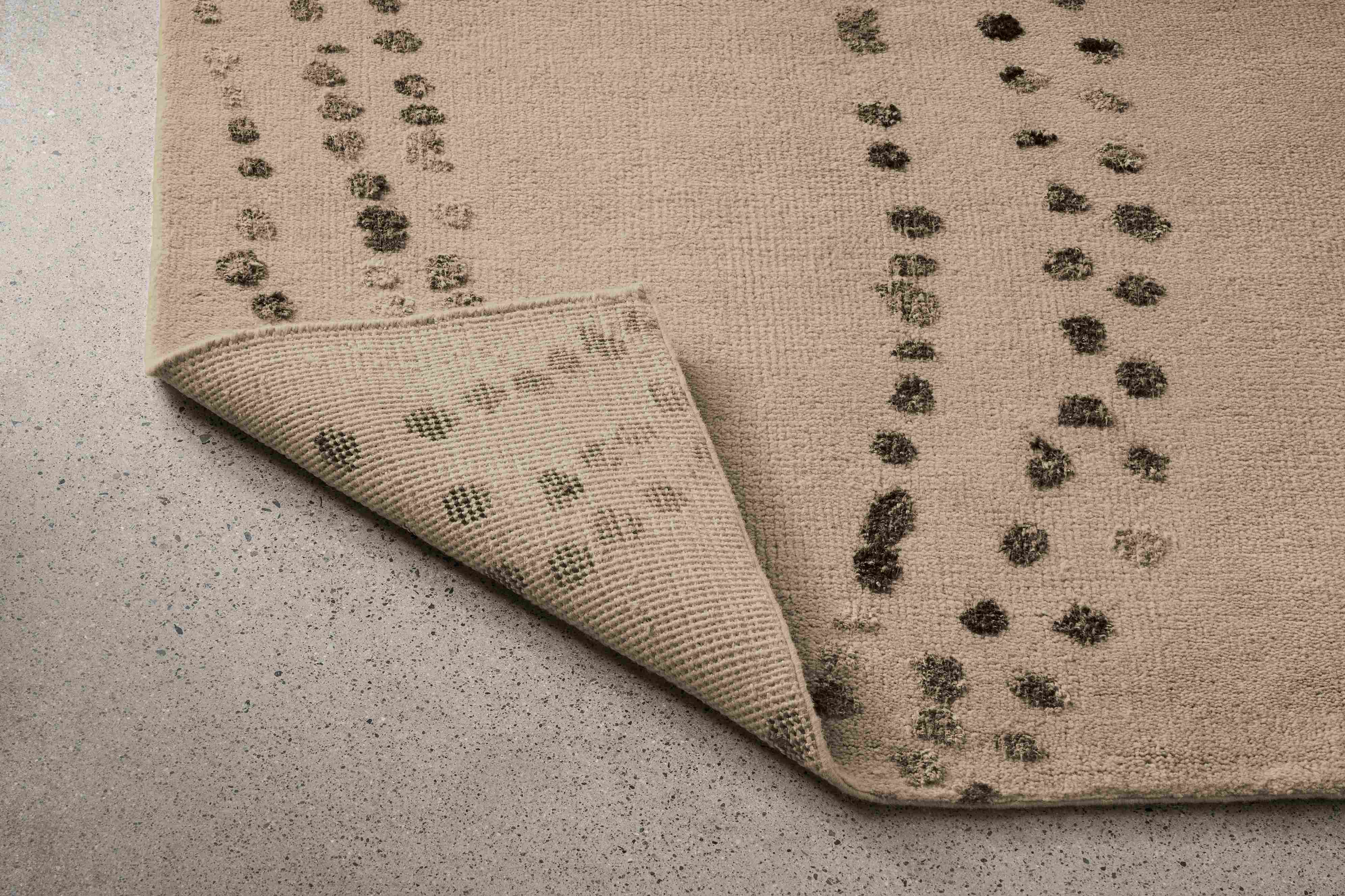 Detail of Sitara 8 by 10 rug in pewter with corner folded up to show underside of rug.