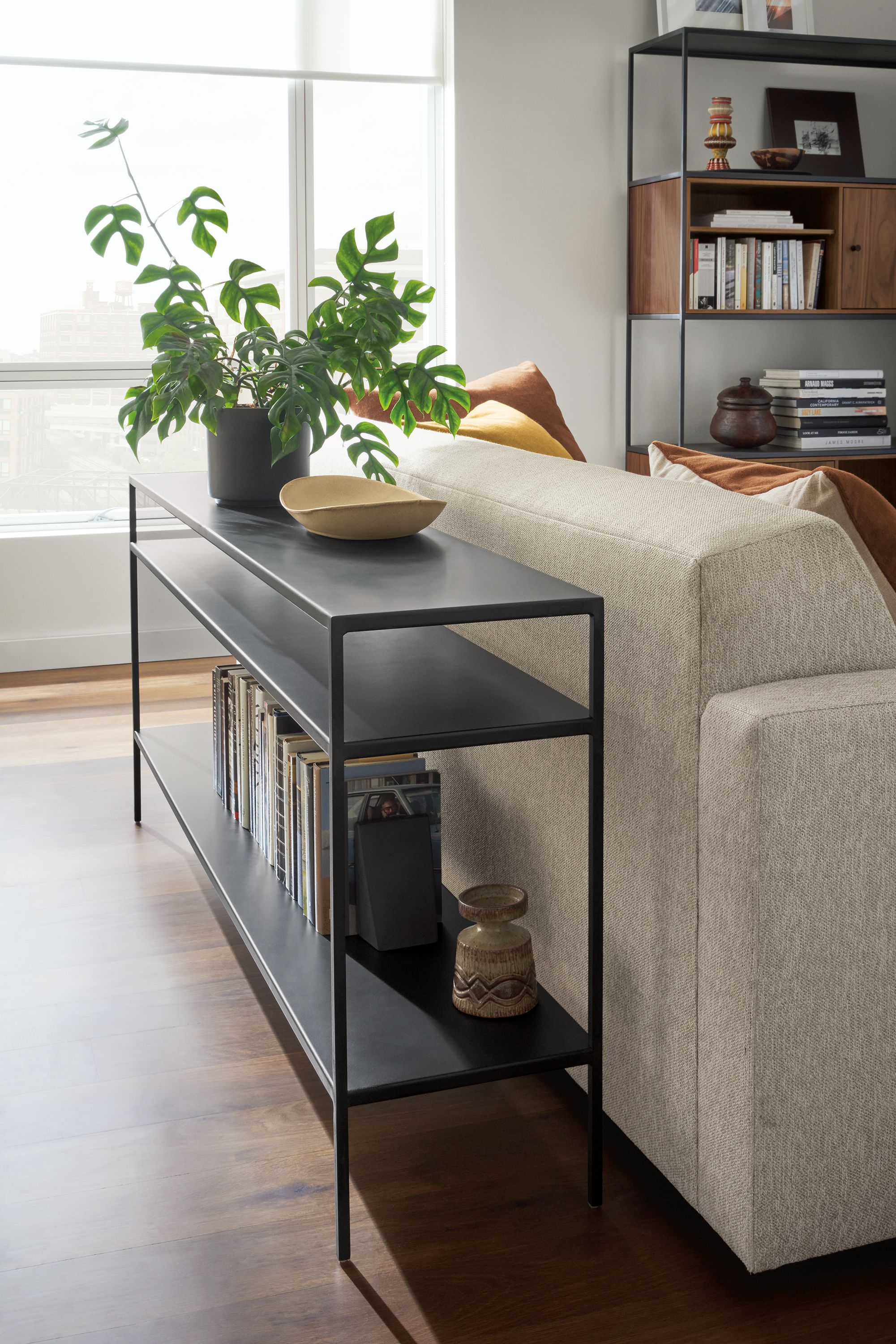 Living room with slim 60-wide console table in natural steel, alex sofa and slim bookcase with walnut inserts.